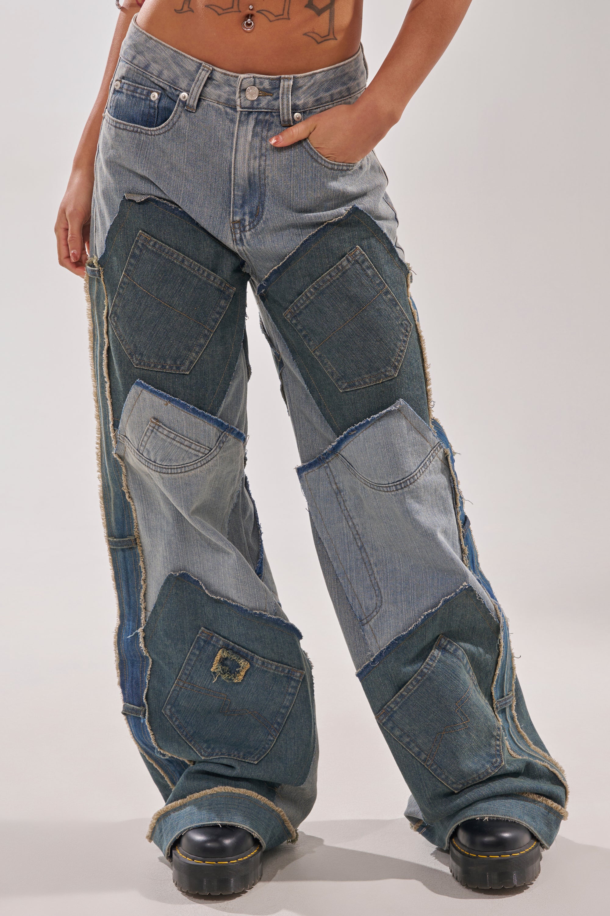 Someone wears ALL THAT WIDE LEG DENIM JEANS, showcasing Y2K street style with distressed patchwork, varied denim shades, large pockets, and raw hems. Black chunky-soled shoes complete the look, with hands and torso relaxed in their pockets. 1