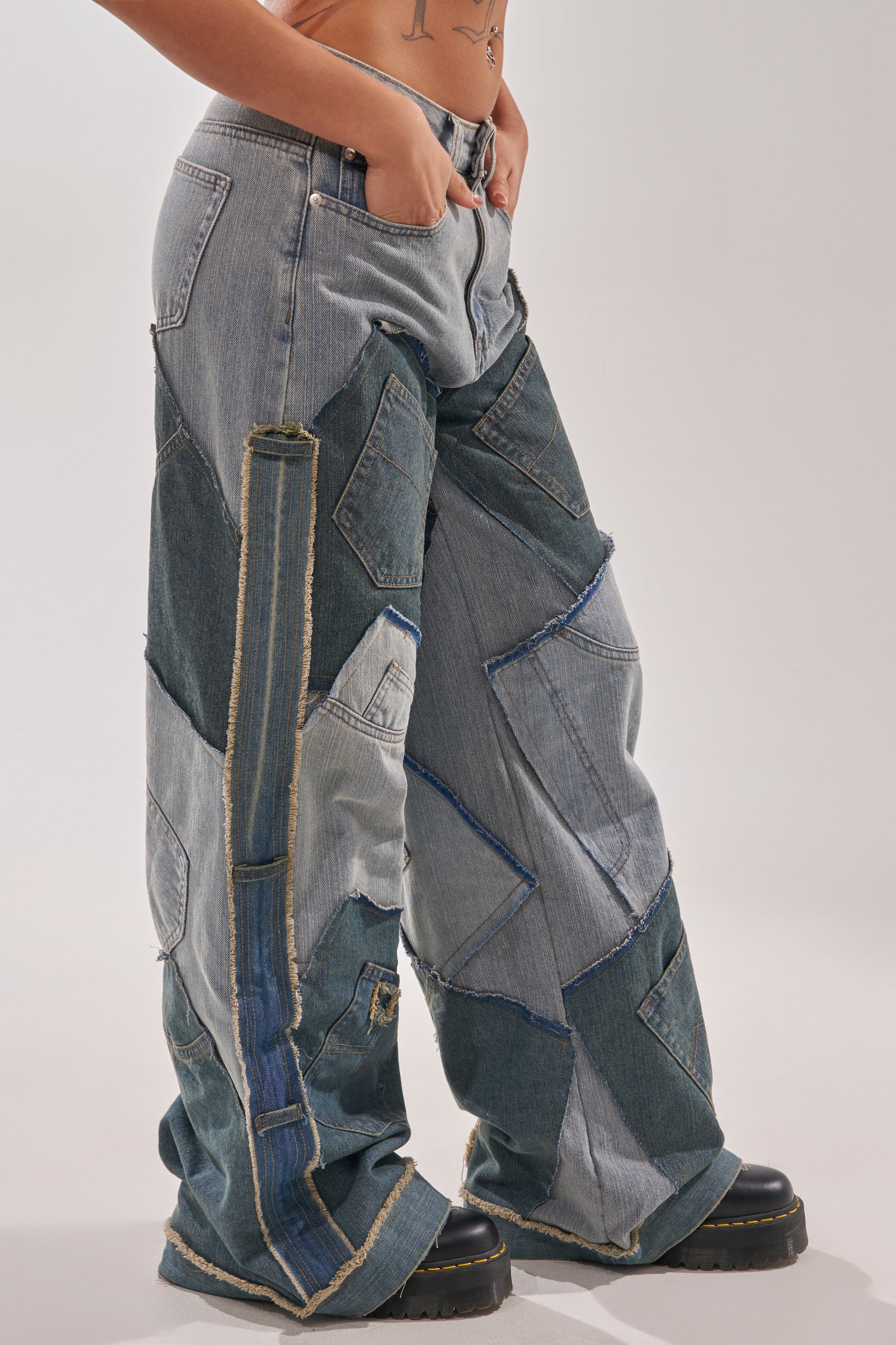 A person models the ALL THAT WIDE LEG DENIM JEANS, inspired by Y2K street style, paired with black platform shoes, standing against a plain background with one hand in their pocket. 2