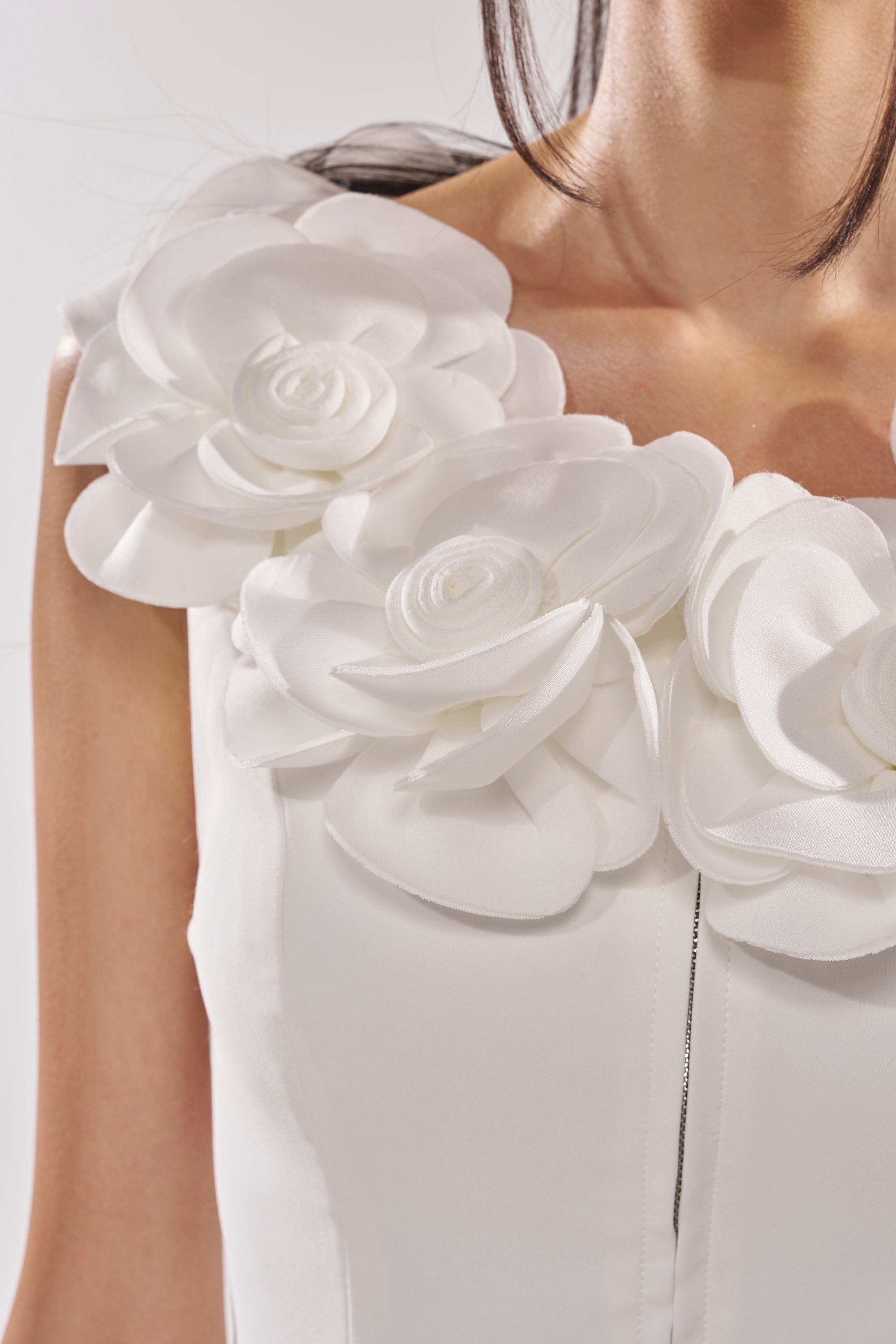 Close-up of a woman in the BRING ME FLOWERS BLOUSE, which features 3D rosette appliqué on the shoulders and neckline. Only her shoulders, upper chest, and part of her hair are visible. 8