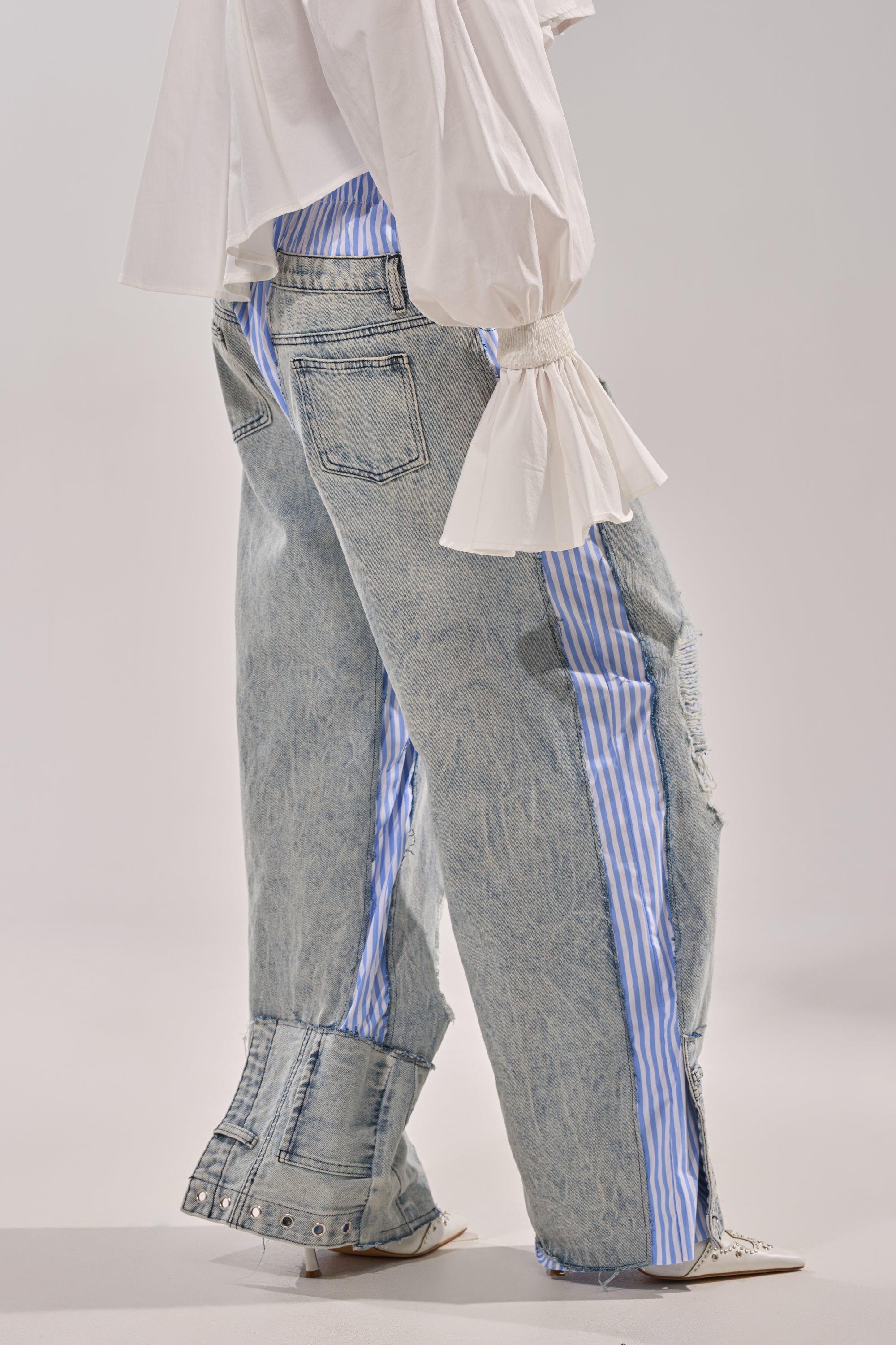 Wearing CALL IT WHAT YOU WANT MIXED UP TROUSER with boxer stripe detailing and a white flared-sleeve blouse, this look stands out against a plain light background for chic street-style appeal. 2