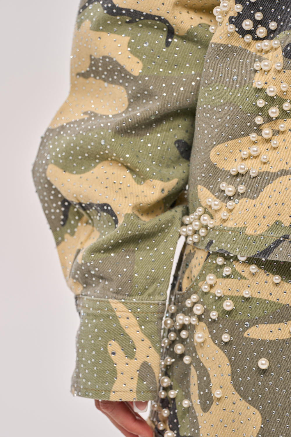 Close-up of the EMBELLISHED CAMO BUTTON DOWN, featuring pearl and rhinestone details with intricate button accents on the sleeve and side. 10