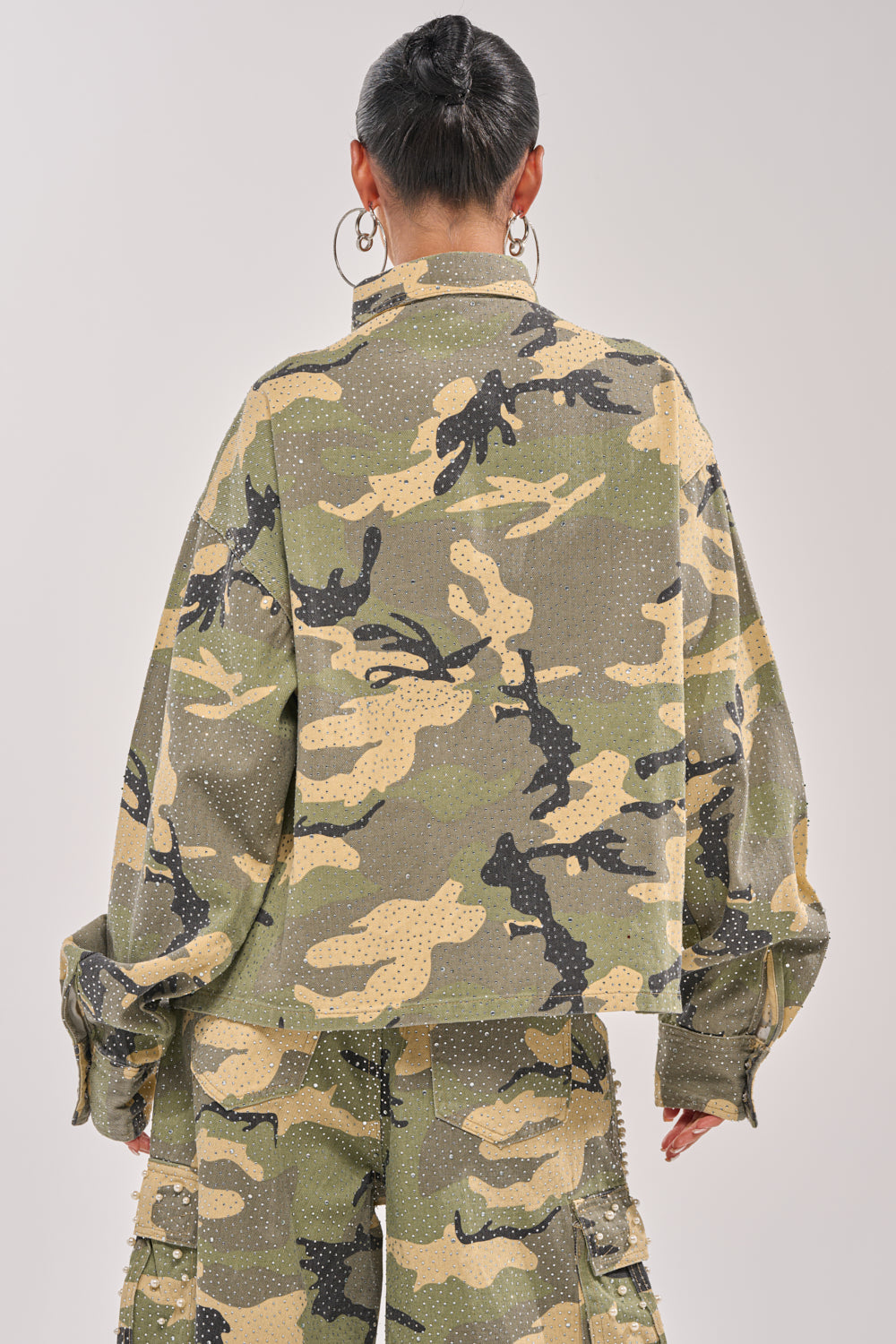 A person with short dark hair and large hoop earrings is seen from the back, wearing the EMBELLISHED CAMO BUTTON DOWN against a plain light background. 6