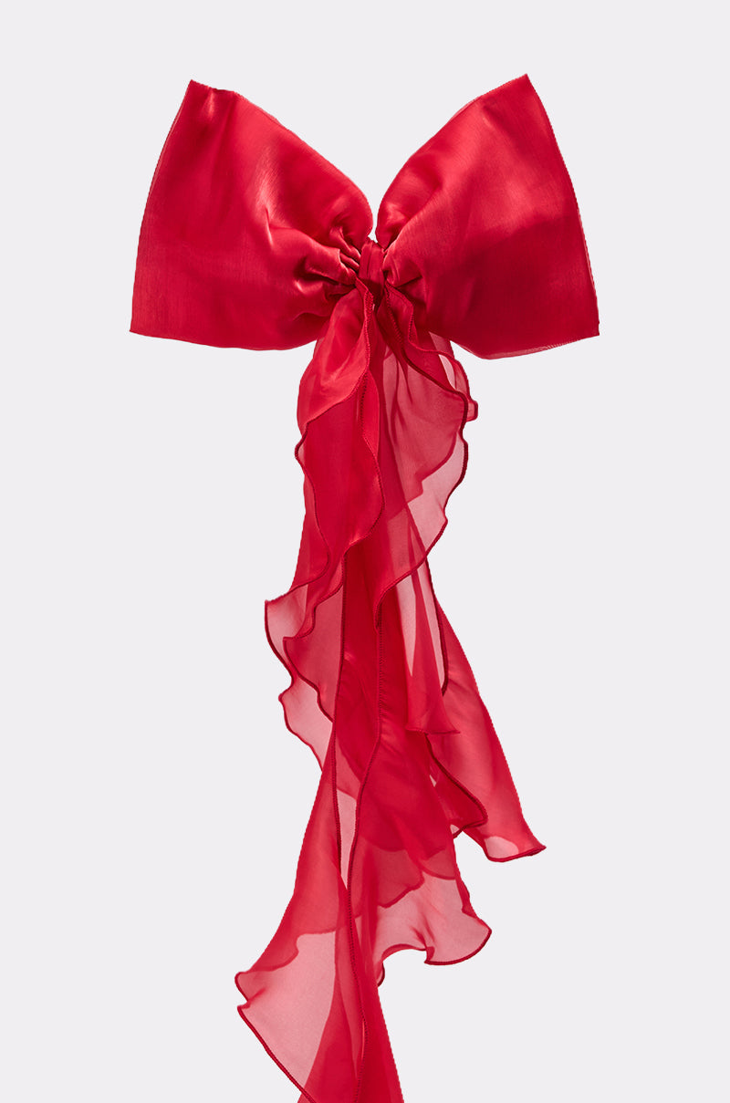 The HEY DOLL CHIFFON HAIR BOW, a large decorative red bow with sheer, flowing chiffon fabric and long wavy tails, is showcased against a plain light background. 3