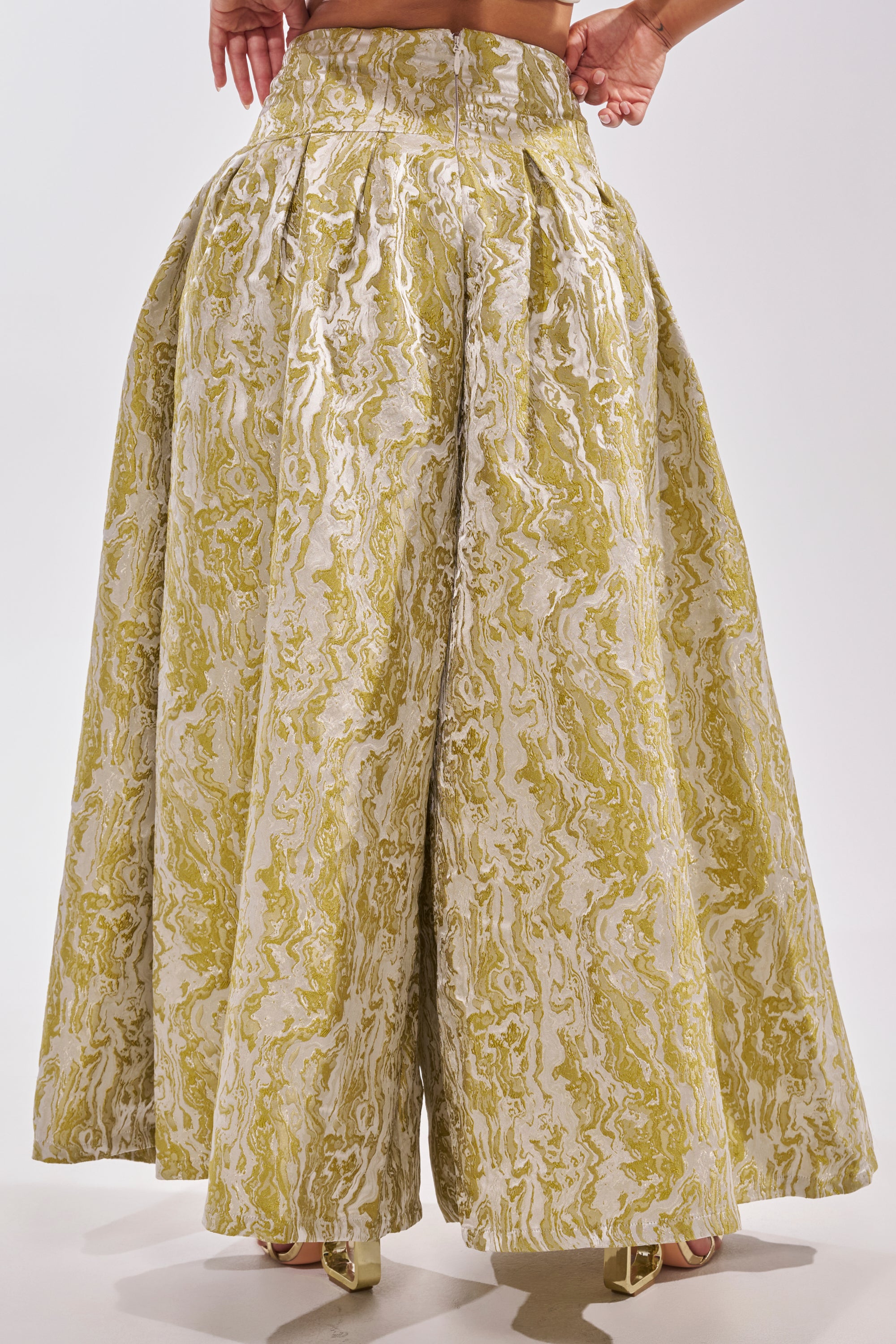 Wearing the GET IT FLORAL TROUSER, featuring a high-waisted, wide-leg silhouette and a yellow-white marbled print, someone stands confidently with hands on hips against a plain background—perfect for standout brunch style inspiration. 5