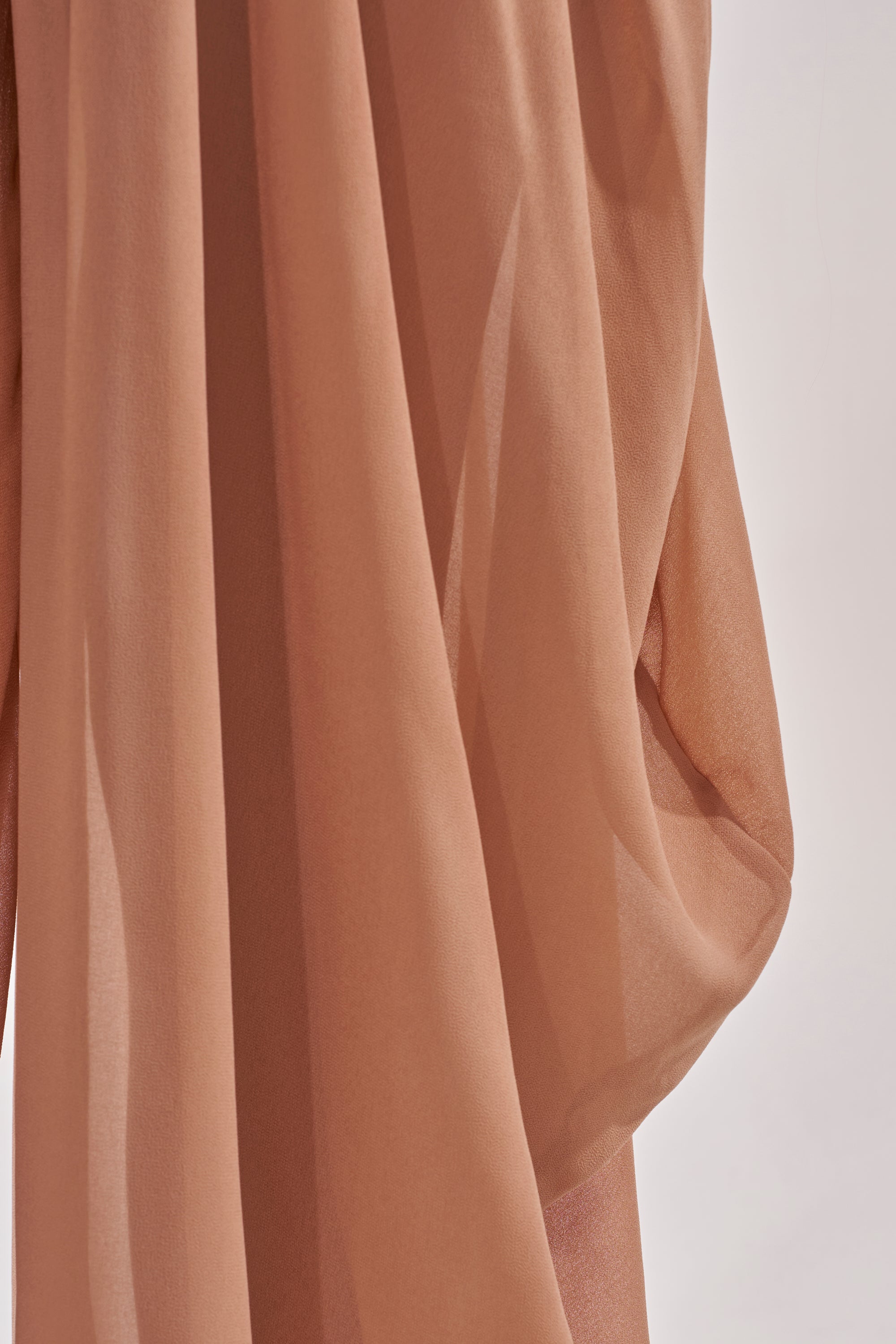 A close-up of the BOUNCIN AROUND BALLOON PANT in sheer light brown fabric, softly draped with gentle folds and subtle shadows, evokes the look of luxurious resort evening wear against a light background. 7