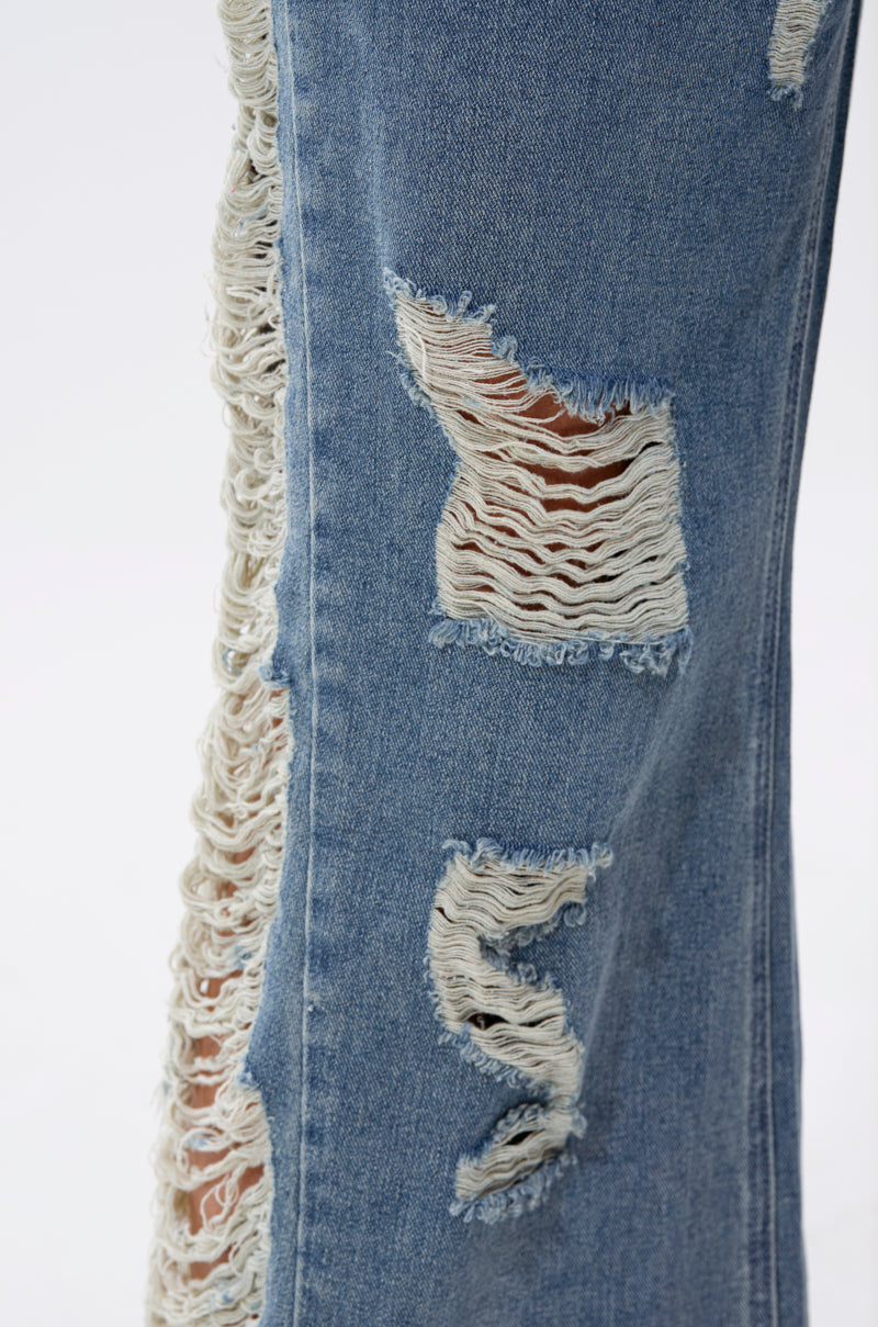 Close-up of the OVER IT DISTRESSED RELAXED DENIM jeans, showcasing wide-leg style with large horizontal rips, frayed edges, and exposed threads for a bold distressed look.