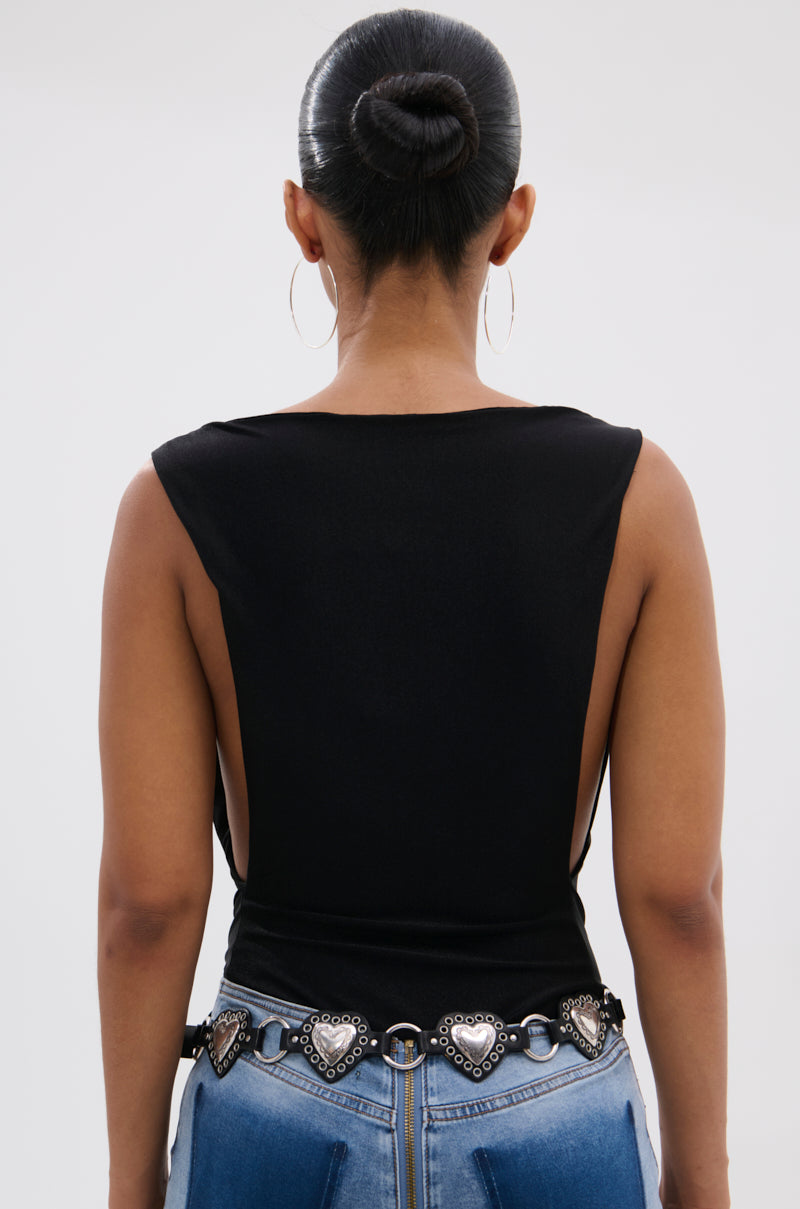 Seen from the back, a person with a sleek bun and hoop earrings wears the SEXY OPEN SIDE BODYSUIT— a sleeveless black one-piece paired with blue jeans and a black belt featuring silver heart-shaped details.