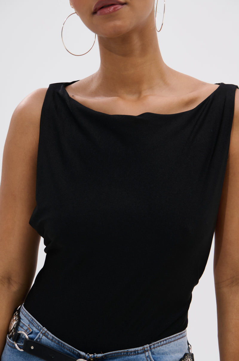 Someone models the SEXY OPEN SIDE BODYSUIT, a sleeveless black style with a draped neckline and curve-skimming fit, paired with light blue jeans and large hoop earrings, shown from shoulders to waist against a plain background.