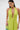 A woman with long dark hair and gold hoop earrings stands against a white background wearing the IN YOUR DREAMS SATIN MIDI DRESS in sleeveless lime green satin with a deep v-neck, and holds a small blue beaded bag.