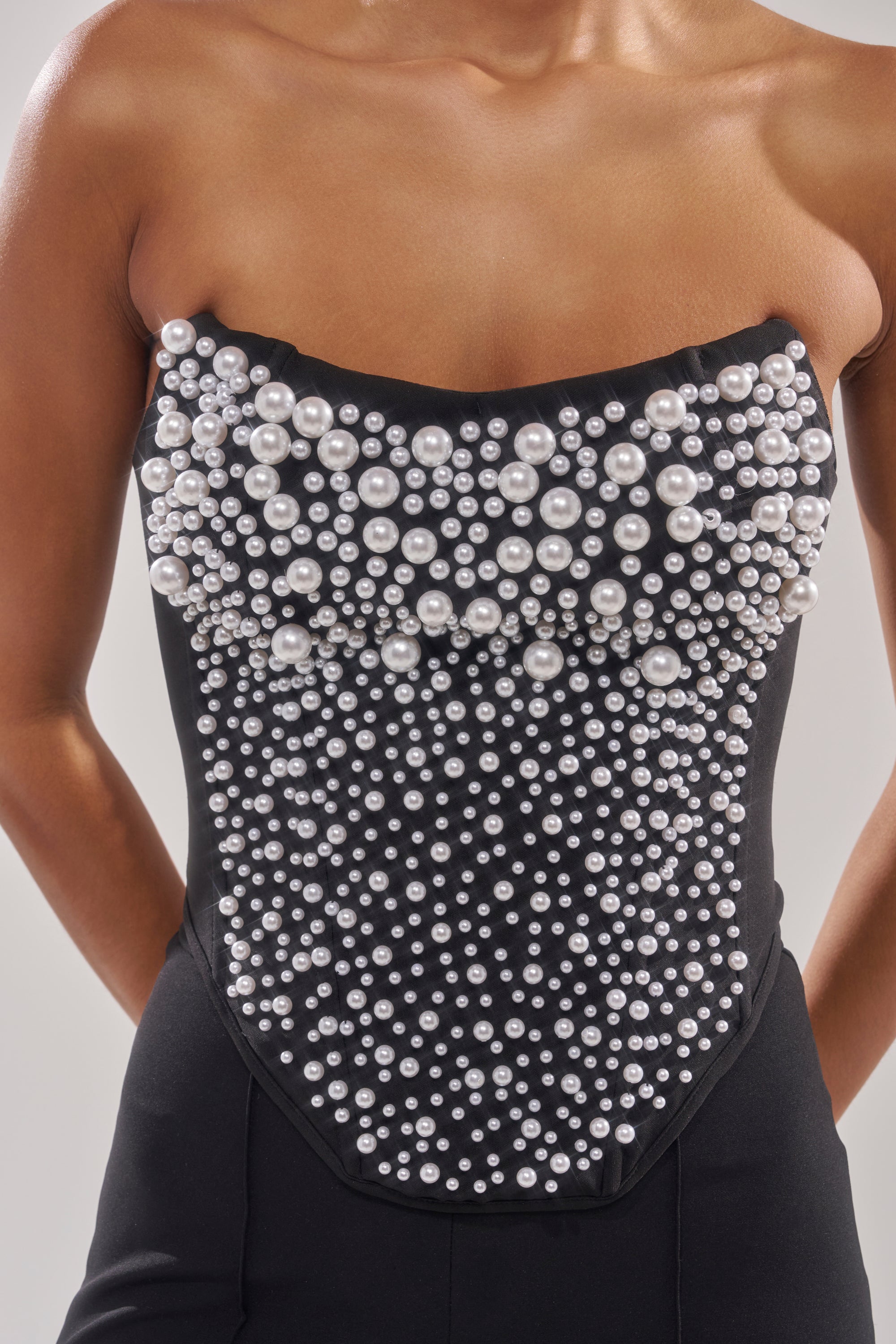 Wearing the NEVER YOURS ALL OVER PEARL CORSET, adorned with faux pearls concentrated at the top and scattered downward, they pose gracefully with their arms behind their back. 7