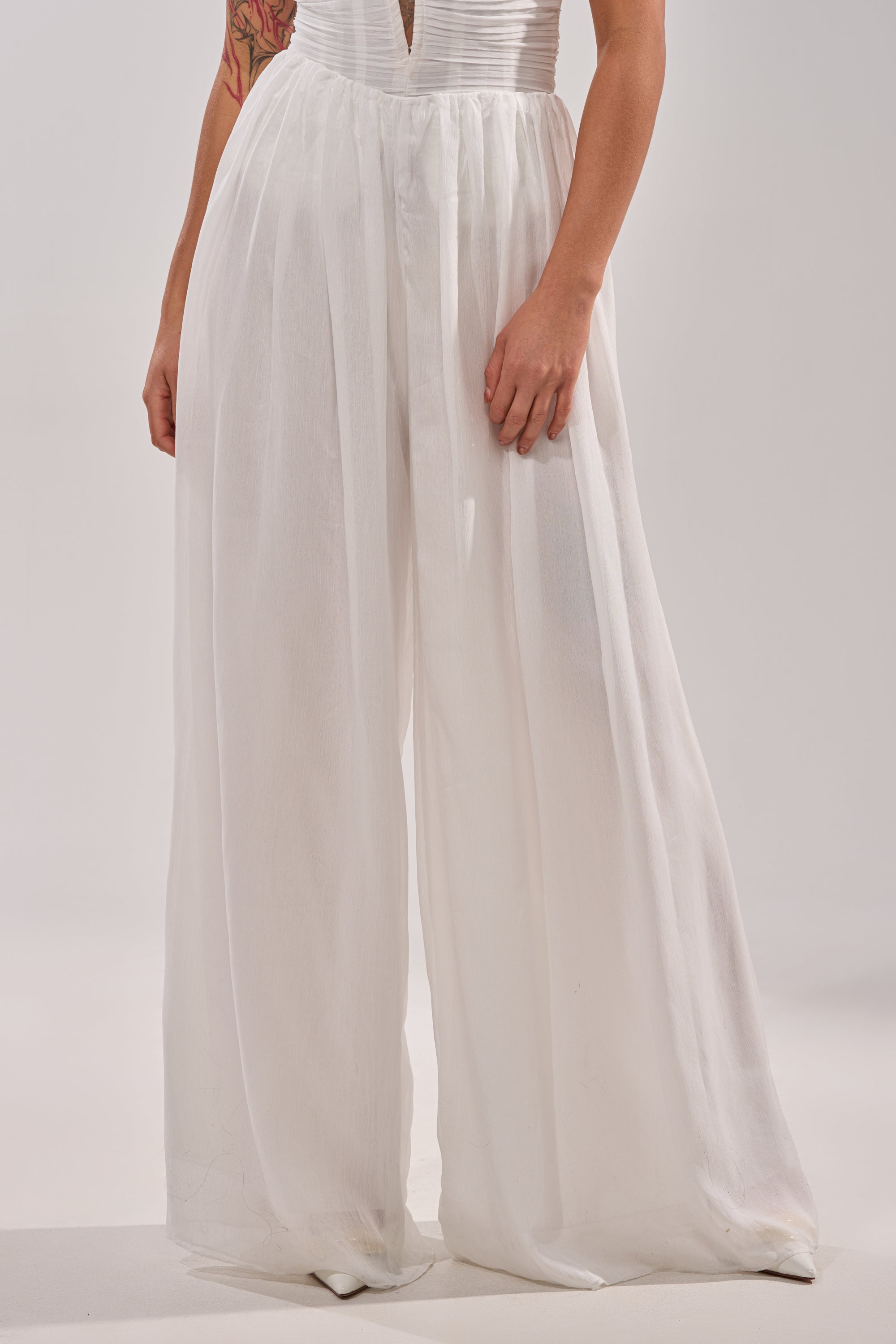 Model showcases the BEAUTIFUL WHITE PALAZZO PANT, featuring a high-waisted, sheer white design with a fitted waistband; only the lower half is visible against a plain light background. 1