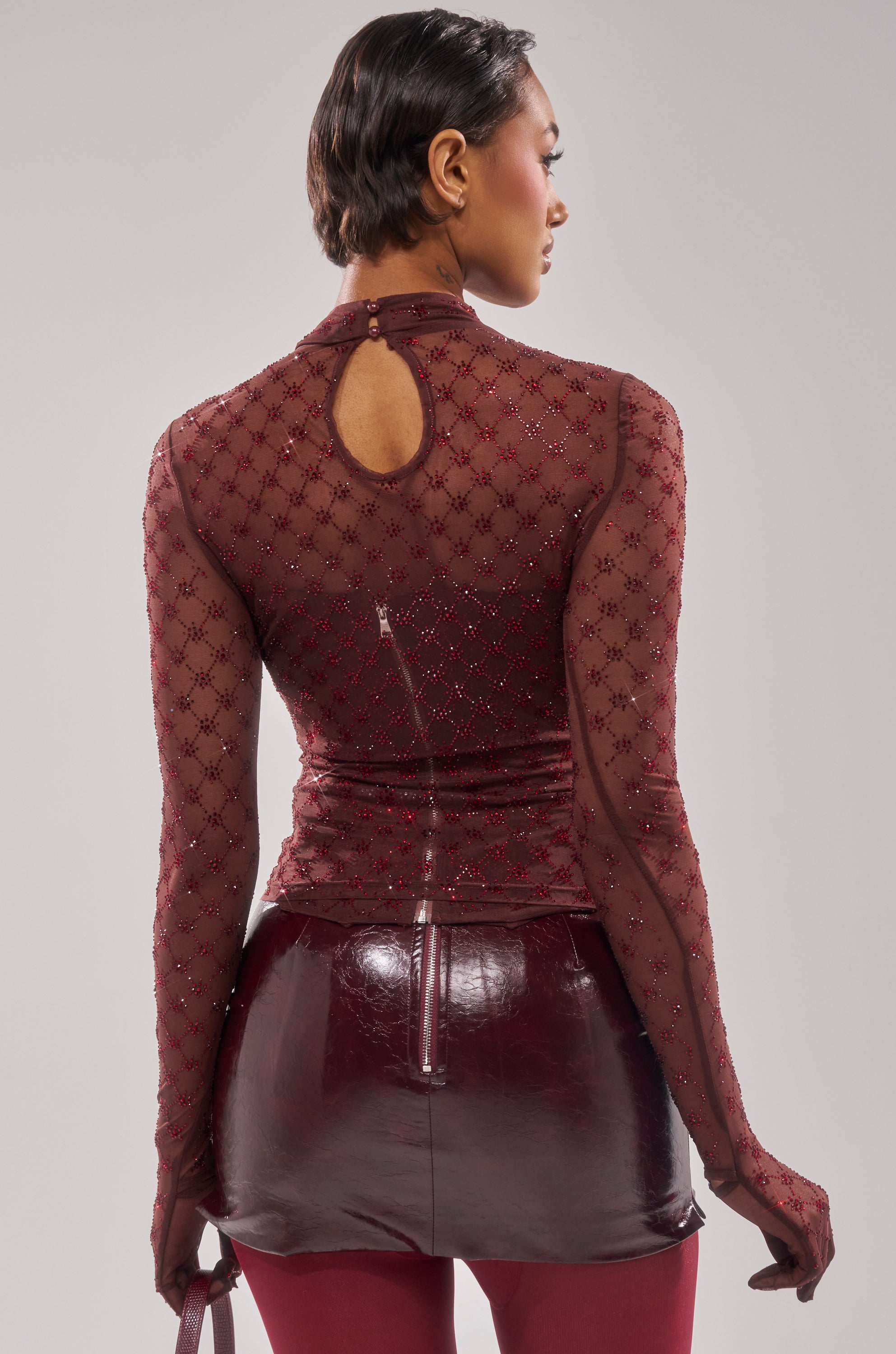 A woman seen from the back wears the EXTREMELY SEXY MESH LONG SLEEVE WITH CORSET and pairs it with a shiny burgundy mini skirt and matching pants for a stunning, coordinated look. 5