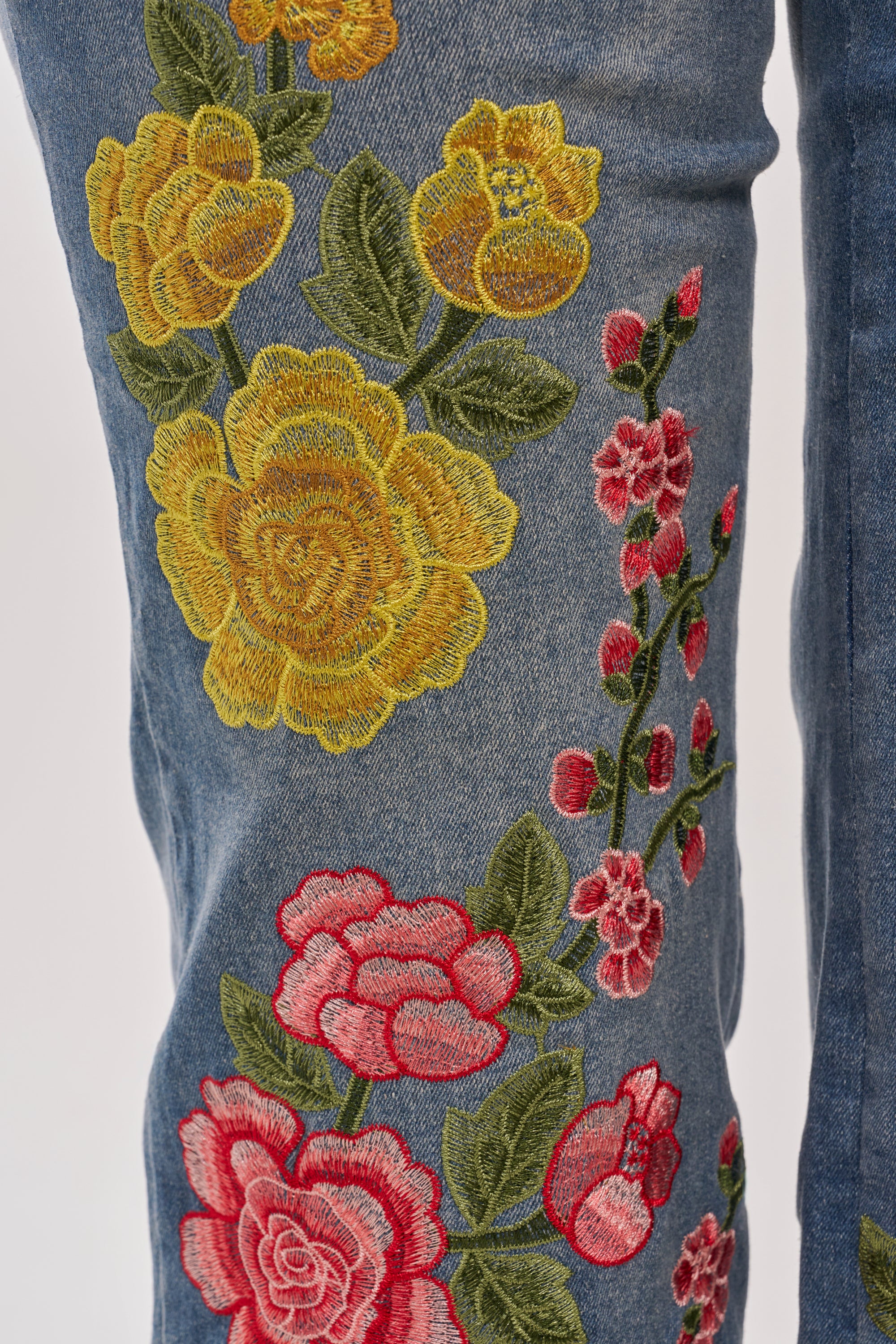 Close-up of FLORAL FOR DAYS STRAIGHT LEG DENIM showcasing vibrant yellow, pink, and red floral embroidery with green leaves for a decorative, eye-catching pattern along the straight-leg jeans. 9