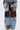 A person models the CALL EM CRAZY PATCHWORK JOGGER—wide-leg jogger pants with denim, corduroy, camo, lace, and colorful fabric patches—standing against a white background for a bold streetwear look.