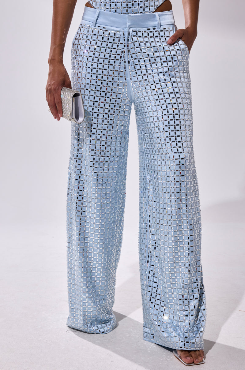 Wearing the LILA EMBELLISHED SATIN TROUSER in powder blue, styled with a small sparkly clutch and open-toe heels; photo cropped to the lower half.