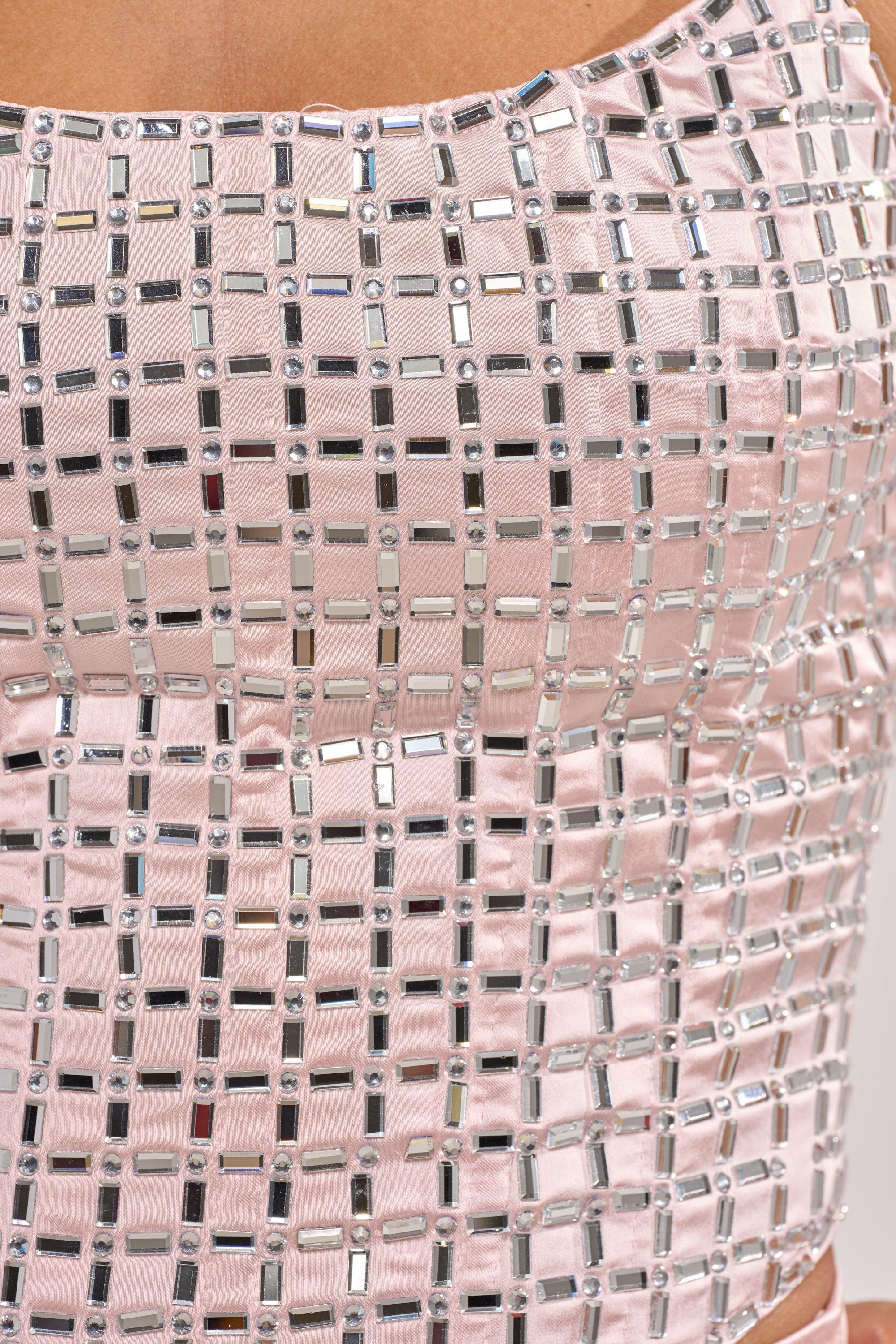 Close-up of a person wearing the LILA EMBELLISHED SATIN CORSET IN LIGHT PINK, featuring shiny pink satin with a grid of small, reflective rhinestones for a sparkling, textured look. 7