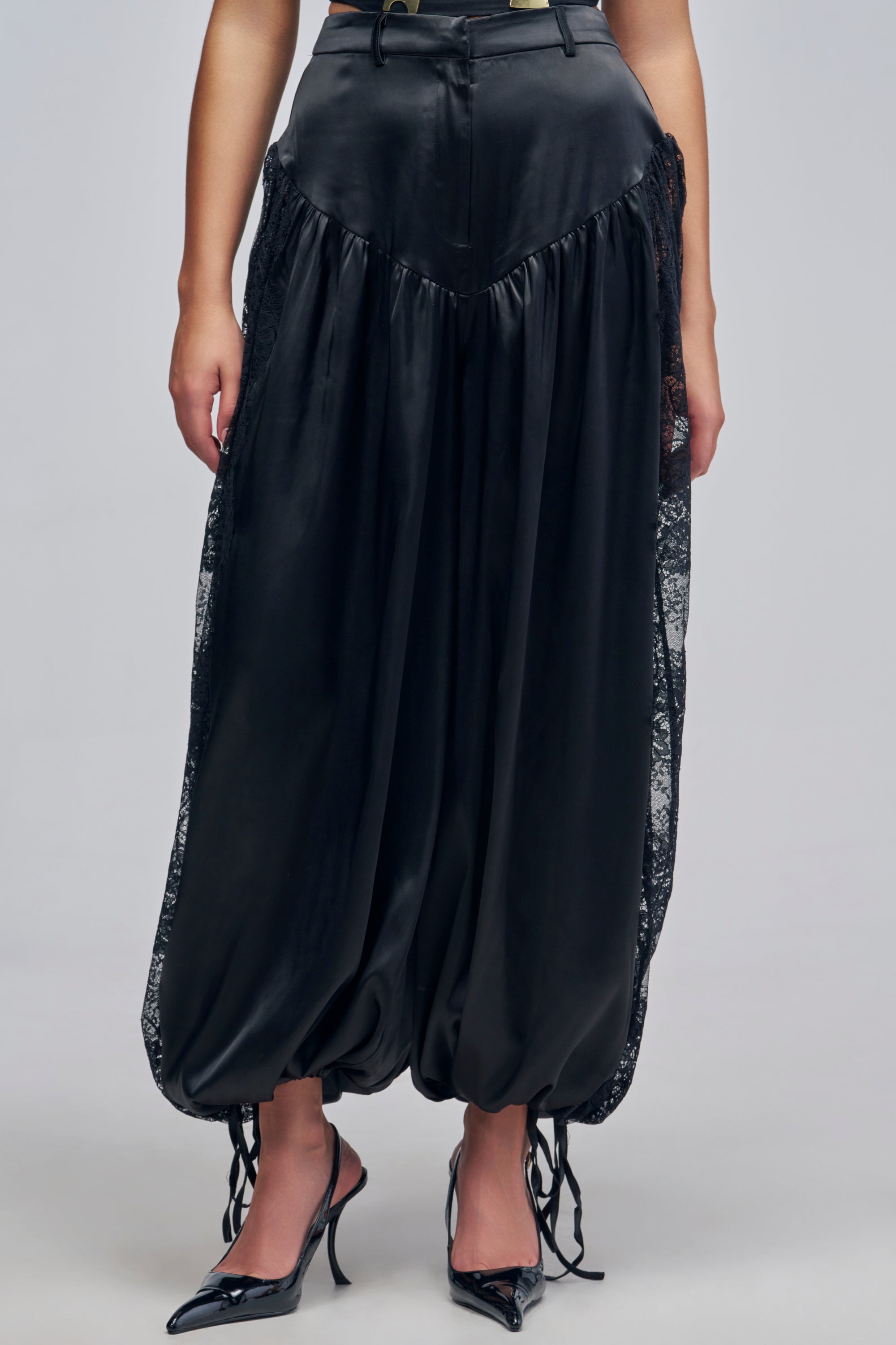 AU CONTRAIRE LACE SATIN BALLOON PANTS in black, featuring a high-rise, wide-leg silhouette with lace side panels and cinched, tied hems.
