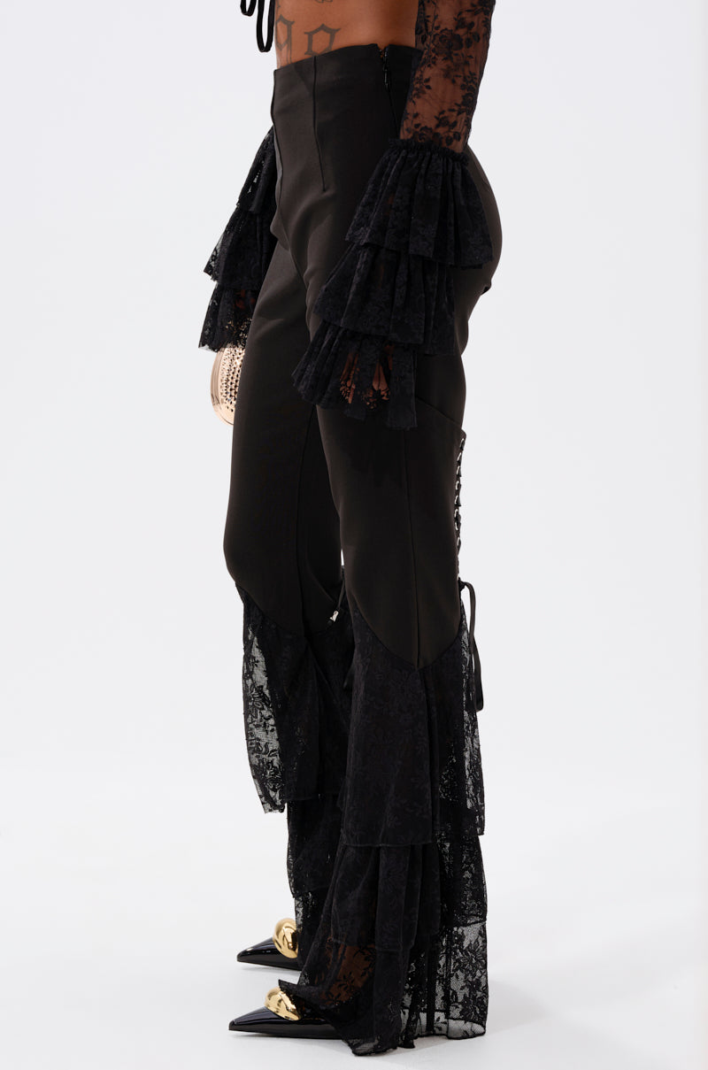 Wearing the LOOKS AND FEELS GOOD LACE FLARE LEGGING with tiered lace ruffles and matching long lace sleeves, paired with black pointed shoes with gold accents, a person poses against a plain white background. 3