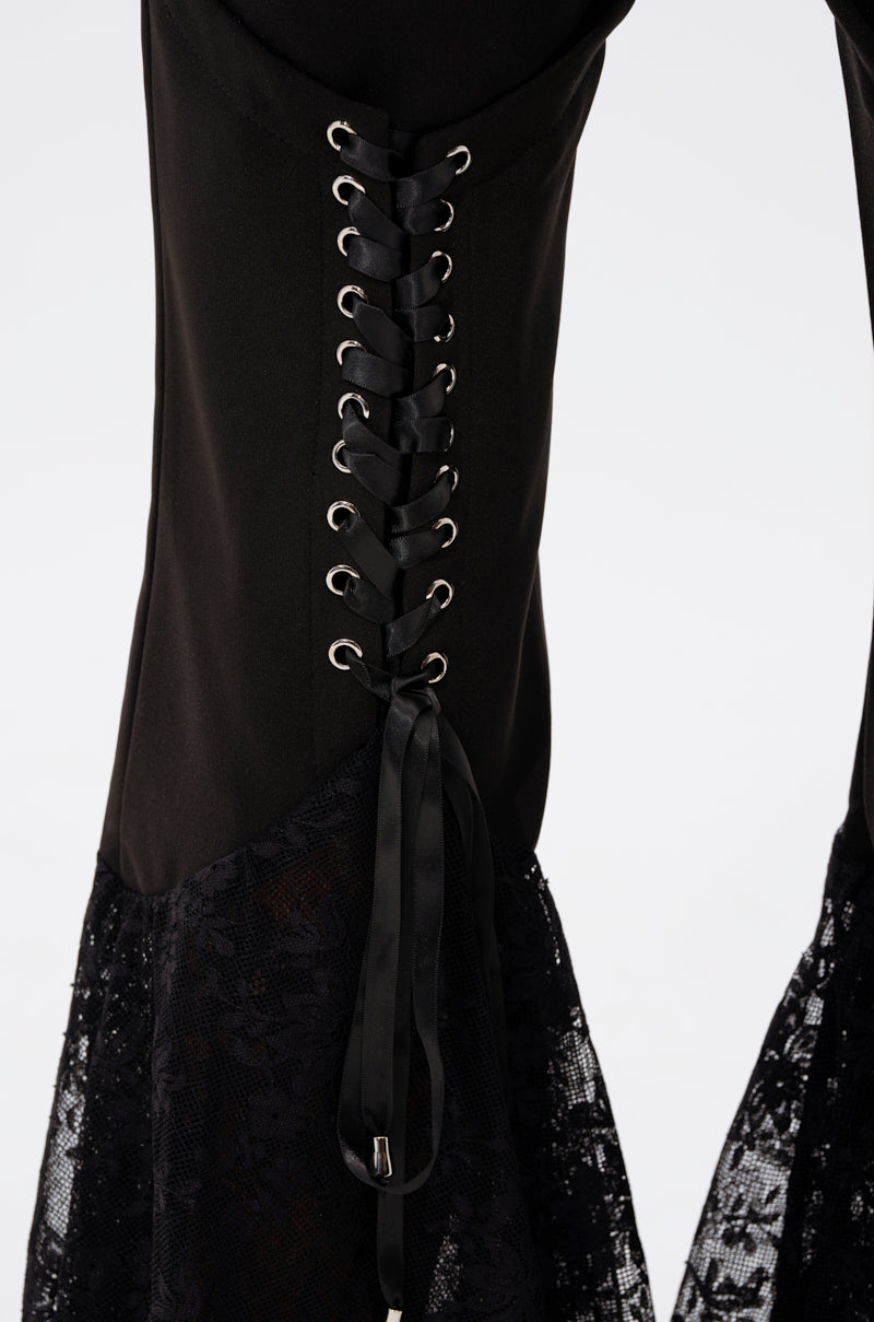 Close-up of the LOOKS AND FEELS GOOD LACE FLARE LEGGING, featuring black lace, silver eyelets with black ribbon lacing, and a sheer flared section. Set against a plain white background. 6