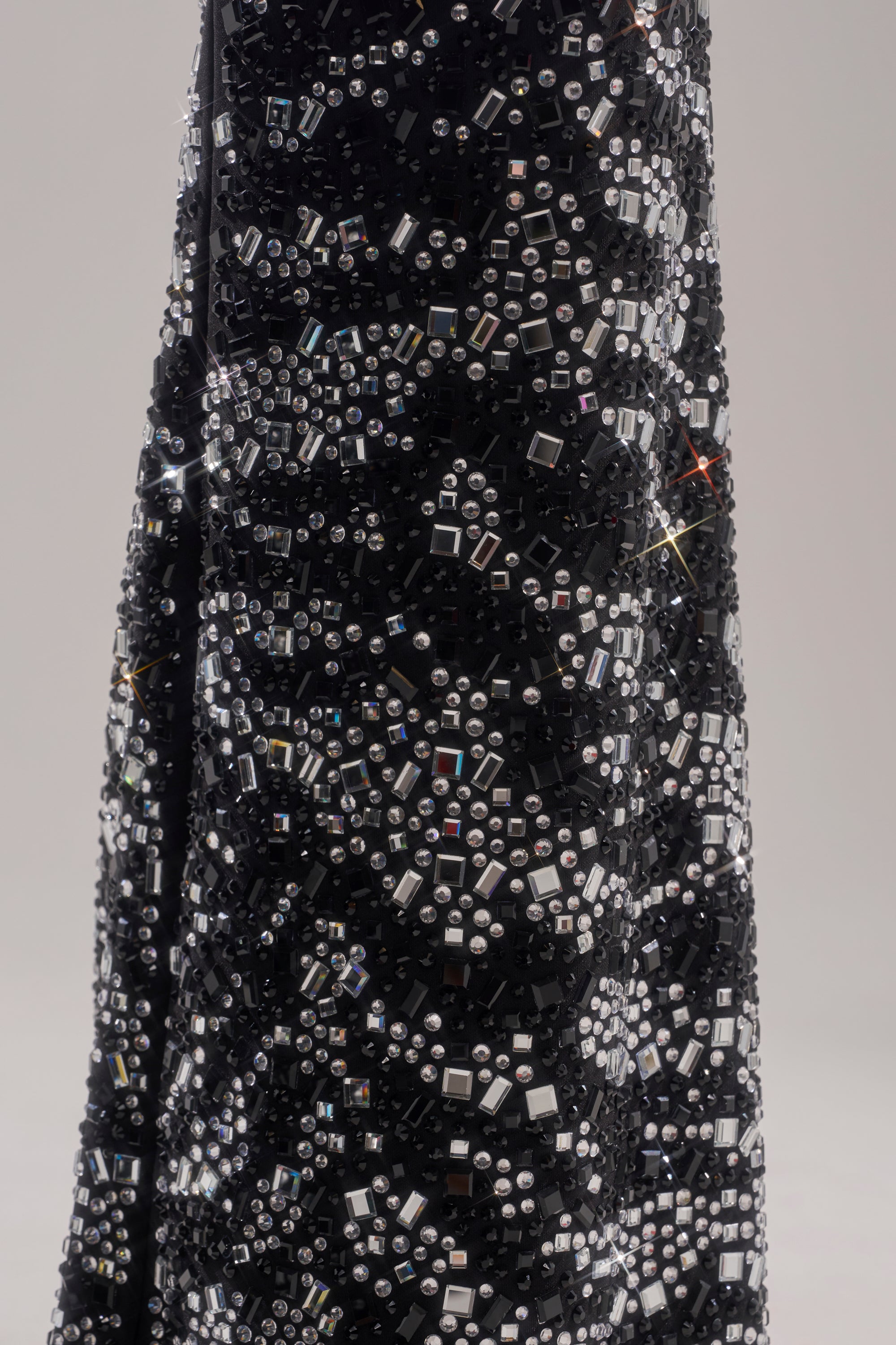 A close-up of the TIME TO CELEBRATE AND DANCE RHINESTONE TROUSER’s black fabric, detailed with sparkling silver and clear beads and sequins in a shimmering geometric pattern, shown against a plain light background.