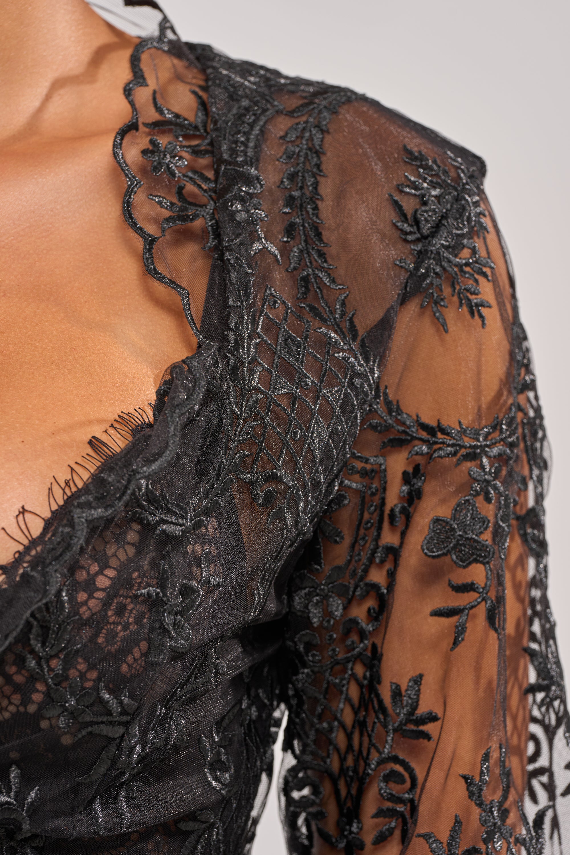 Close-up of the SUPER LUXE LACE TIE-FRONT BLOUSE in sheer black lace with intricate floral and geometric embroidery, showcasing delicate stitching on the chest, shoulder, and upper arm for an elegant look. 7