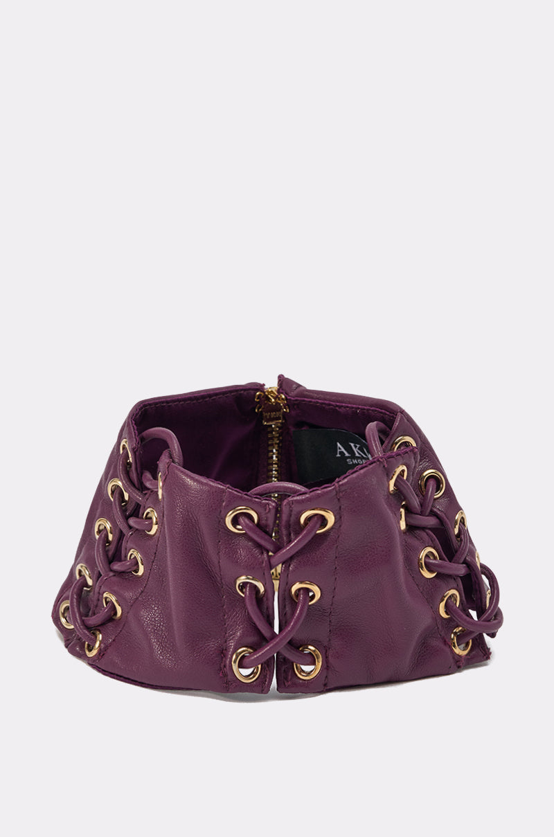 The WHAT THE HELLY CHOKER is a structured purple faux leather choker with gold eyelets, crisscrossed laces, and an inner zipper—a bold decorative accessory. 1