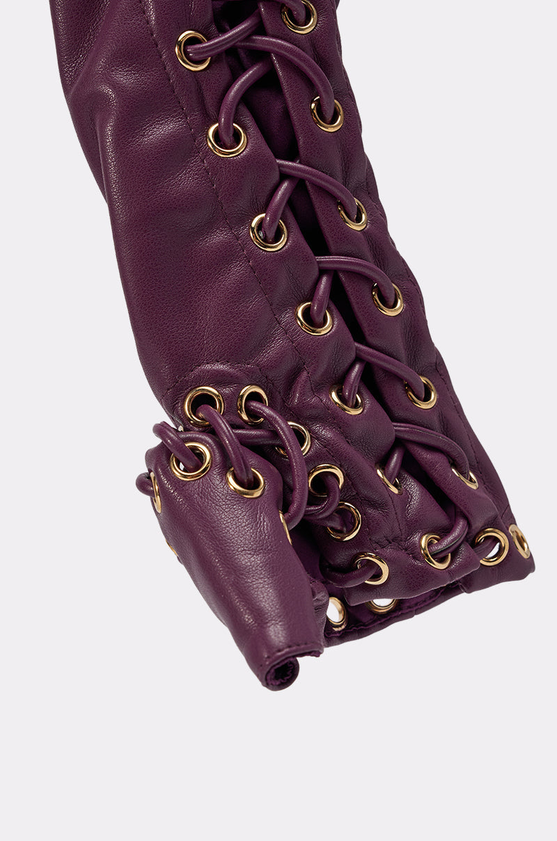 Close-up of WHAT THE HELLY GLOVES in purple faux leather, showcasing gold eyelets and crisscross lacing detail for a gathered, textured look, set against a light grey background. 8