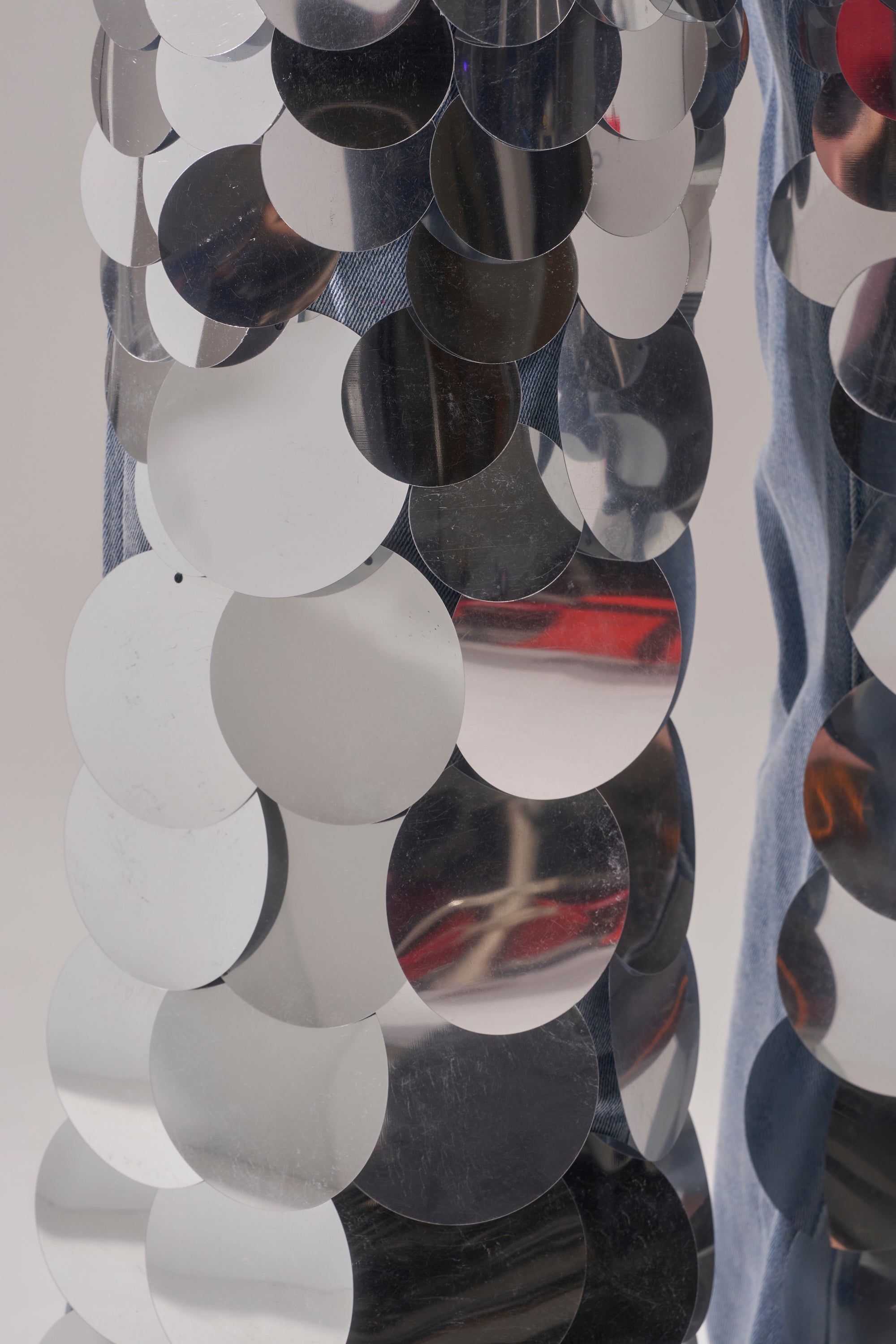 Close-up of large, round silver sequins on blue denim fabric—CHECK IT OUT SEQUIN DENIM PANT delivers a bold, textured, and shiny look, perfect for standout party outfits.