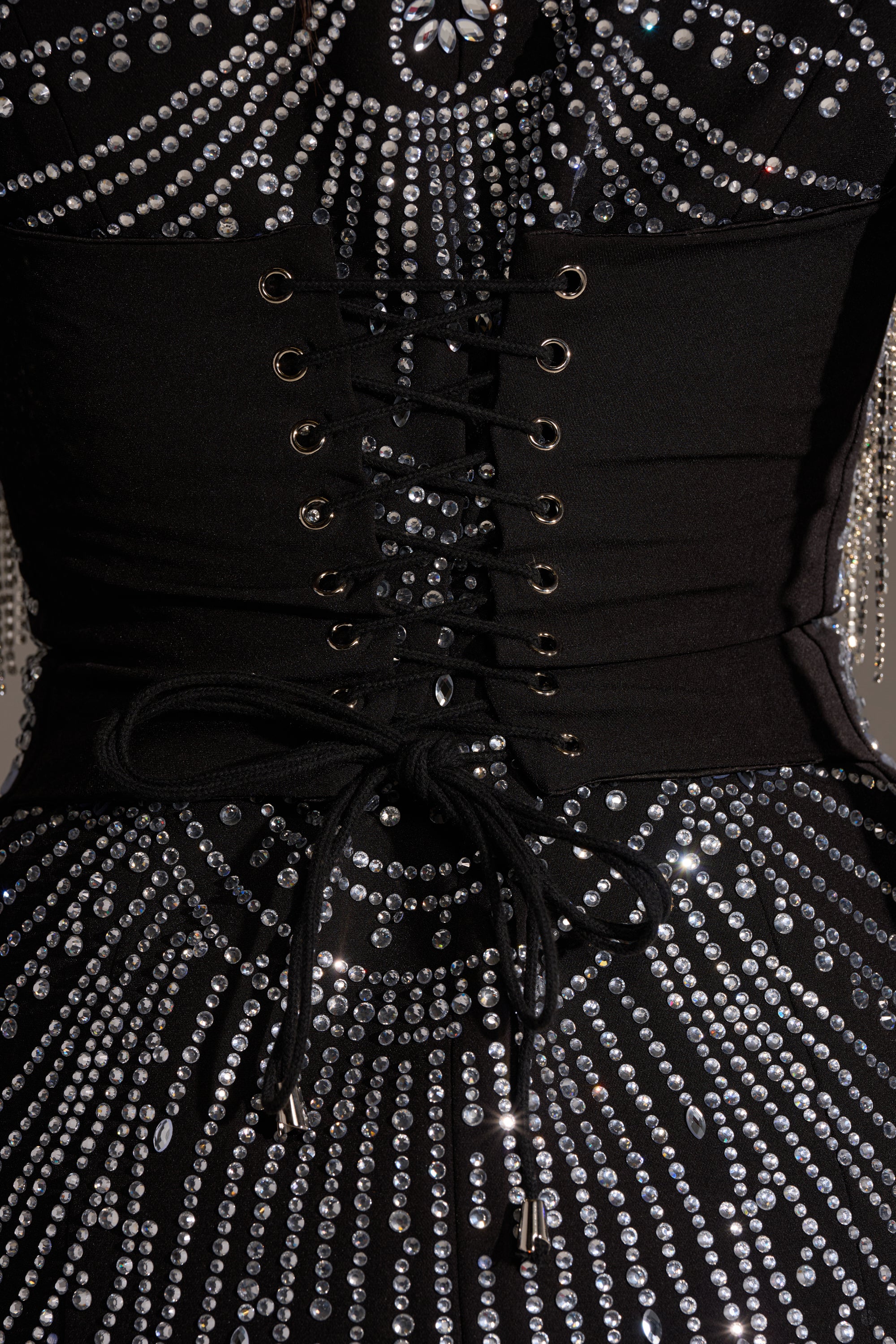 Close-up of the NOT YOUR BABE RHINESTONE BLAZER DRESS, featuring a black mini blazer silhouette with a corset lace-up panel and radiant circular silver rhinestone patterns.