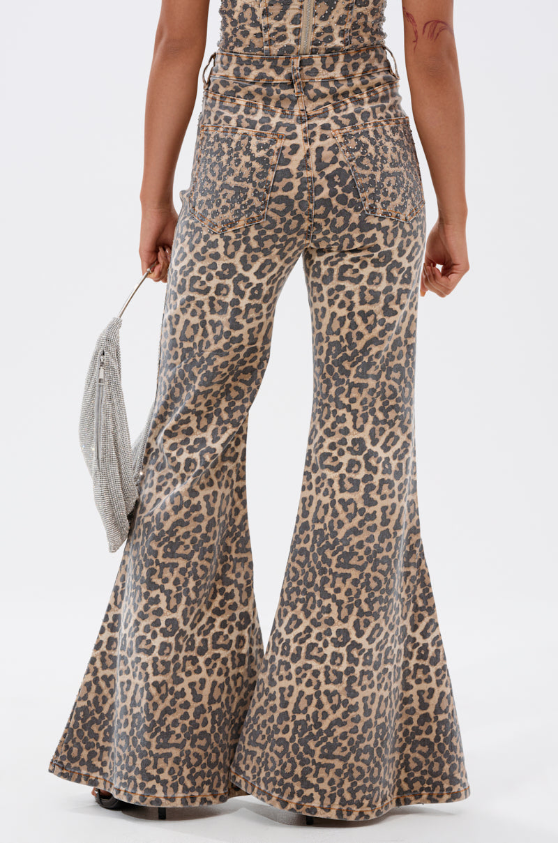 A person models the IN THE WILD WIDE LEG CHEETAH PANT and holds a silver clutch, shown from the back against a white background.
