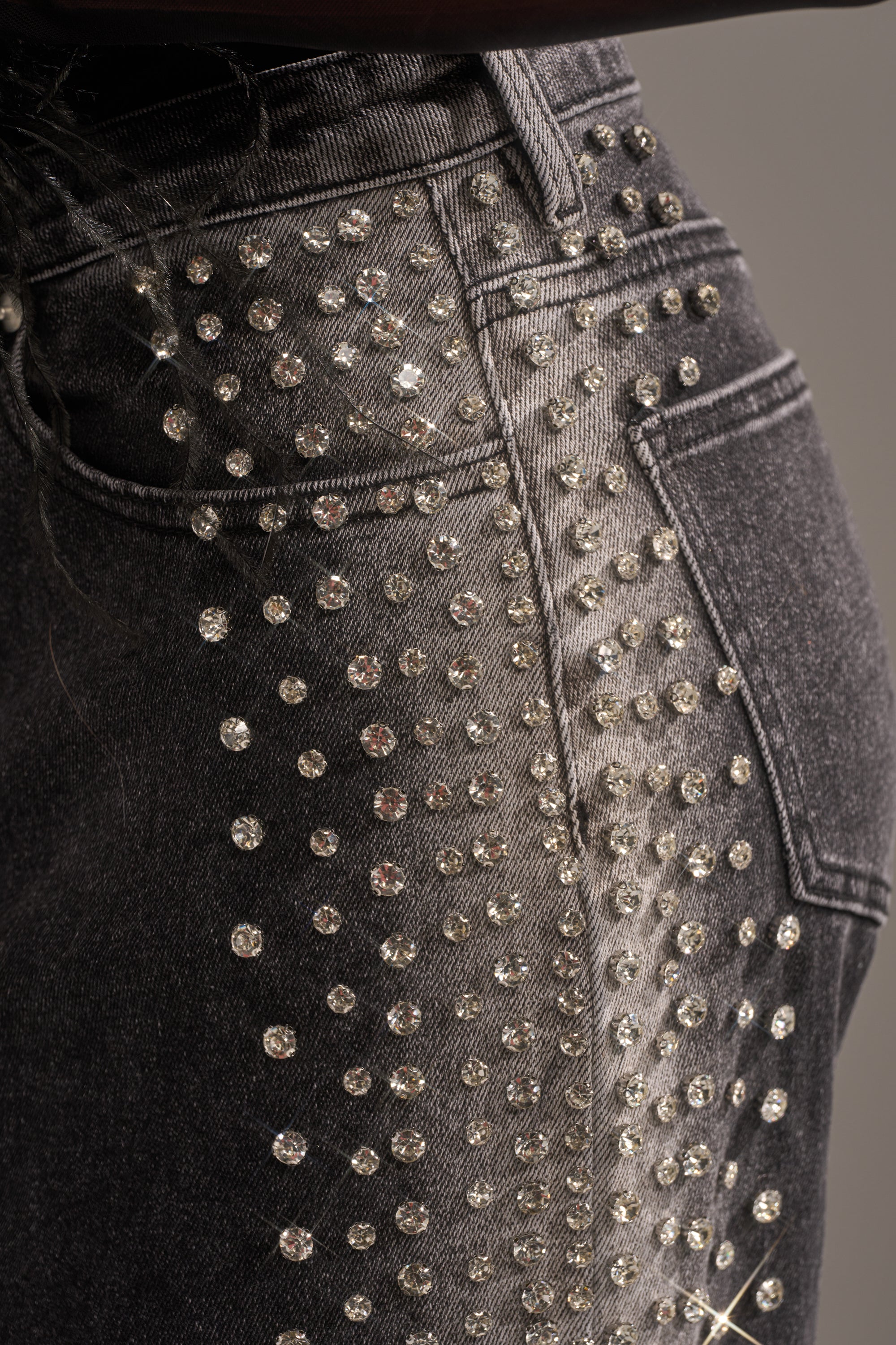 Close-up of FREAKING FIRE EMBELLISHED DENIM, wide-leg jeans adorned with sparkling rhinestones along the pocket and side seam for a glamorous, eye-catching look.