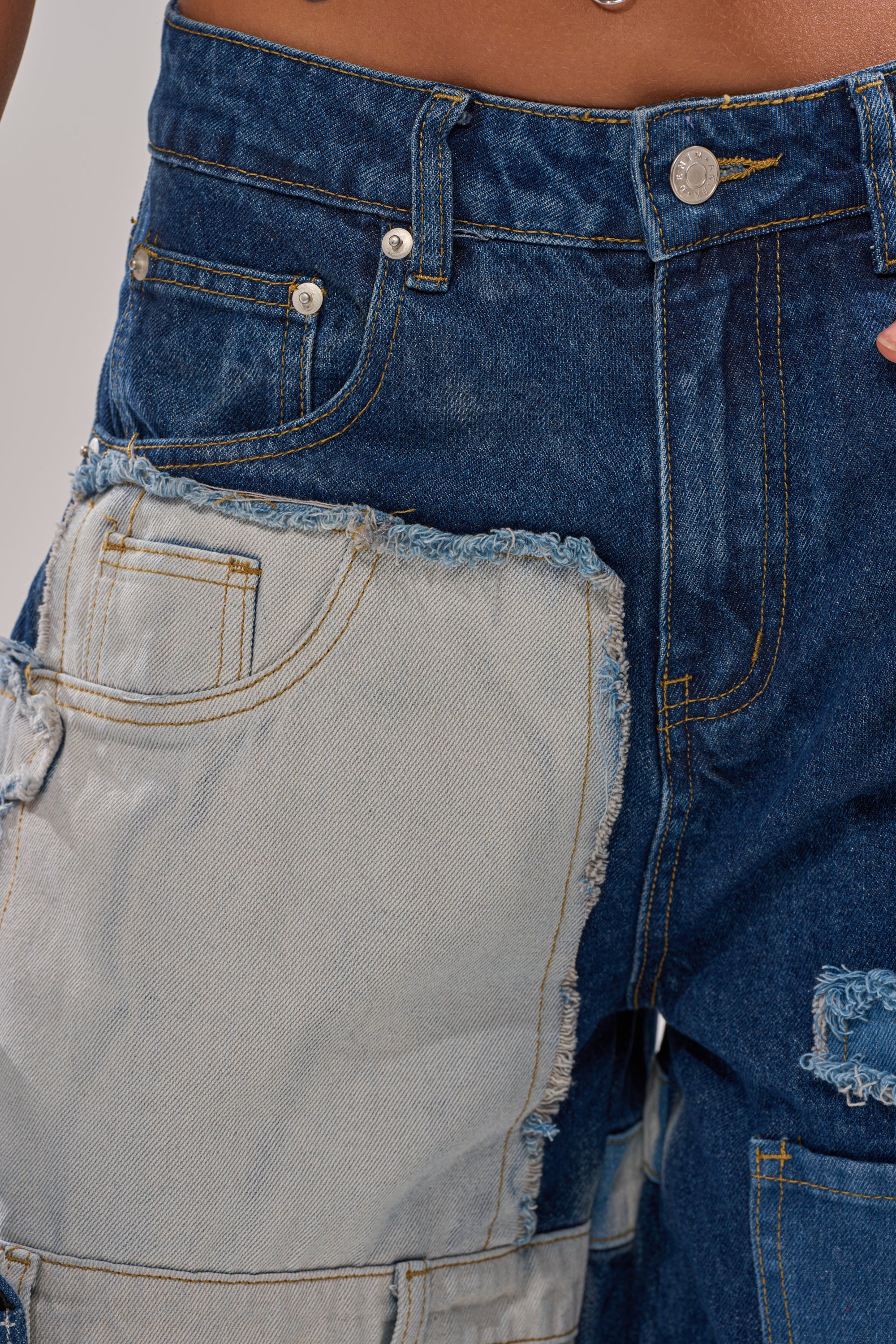 Close-up of the TOO MUCH GOING ON WIDE LEG DENIM, featuring high-waisted patchwork jeans with a large light-wash denim patch and frayed edges on dark blue fabric for a unique style. 7