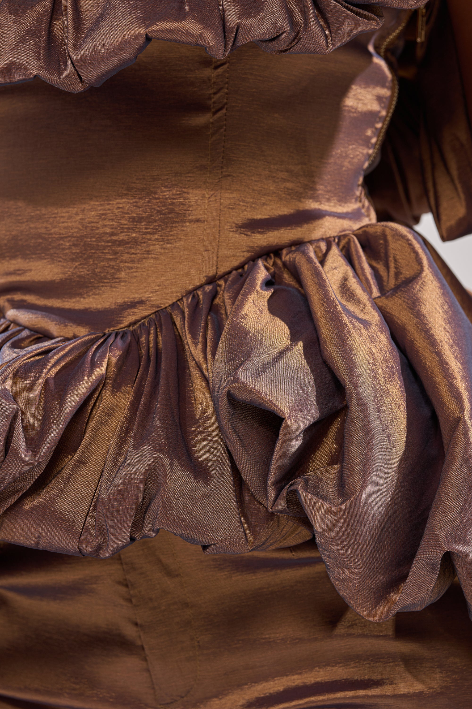 Close-up of the NOT TOO SIMPLE BLOUSE in shiny brown metallic taffeta, featuring gathered and ruffled detailing at the waist and hips, with visible texture and stitching.