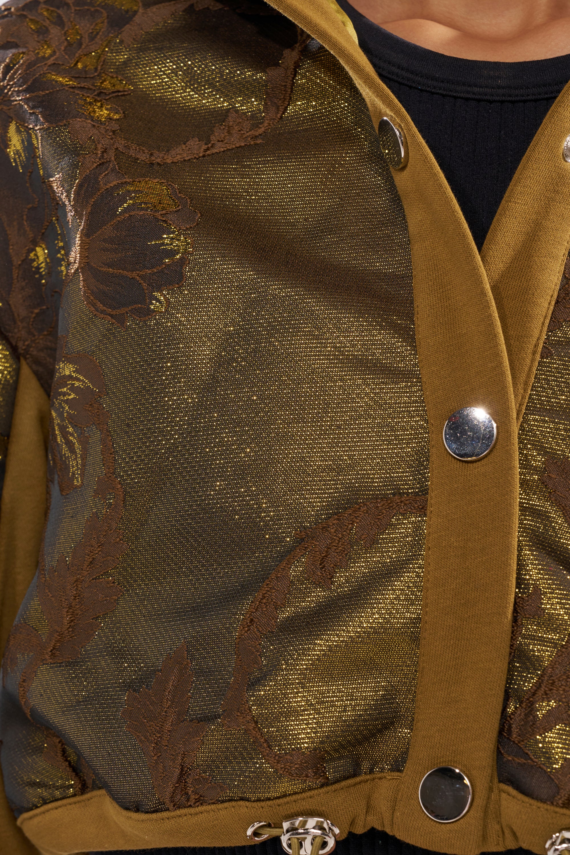 Close-up of the YOU KNOW IT BABY CROP BUTTON DOWN, featuring floral brocade with metallic gold and brown embroidery, gold buttons, and mustard yellow trim, styled as bold streetwear over a black top. 7