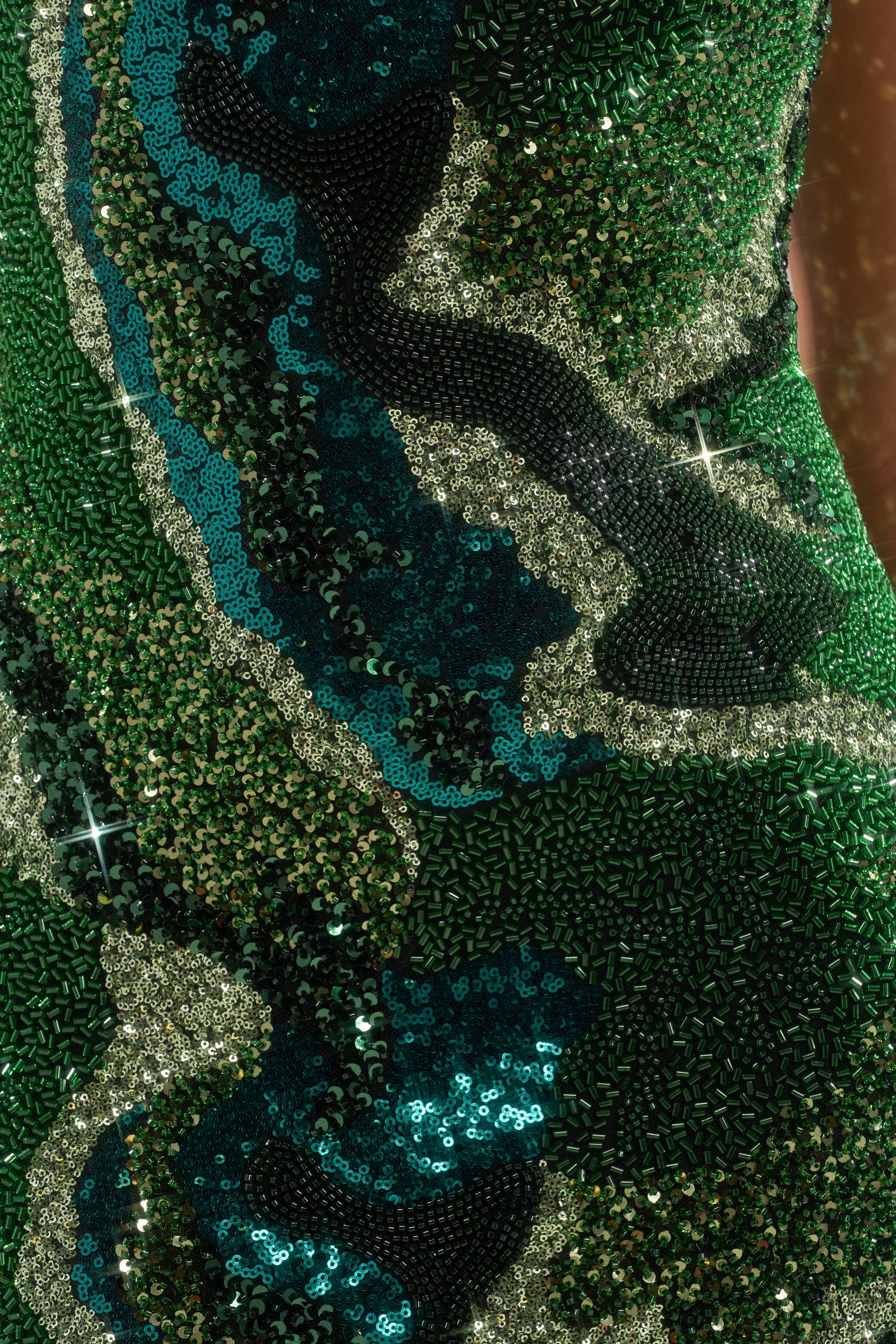 Close-up of the NOT IN THE MOOD SEQUIN MINI DRESS featuring green, blue, black, and silver sequins and beads in wavy abstract patterns that catch the light and sparkle.