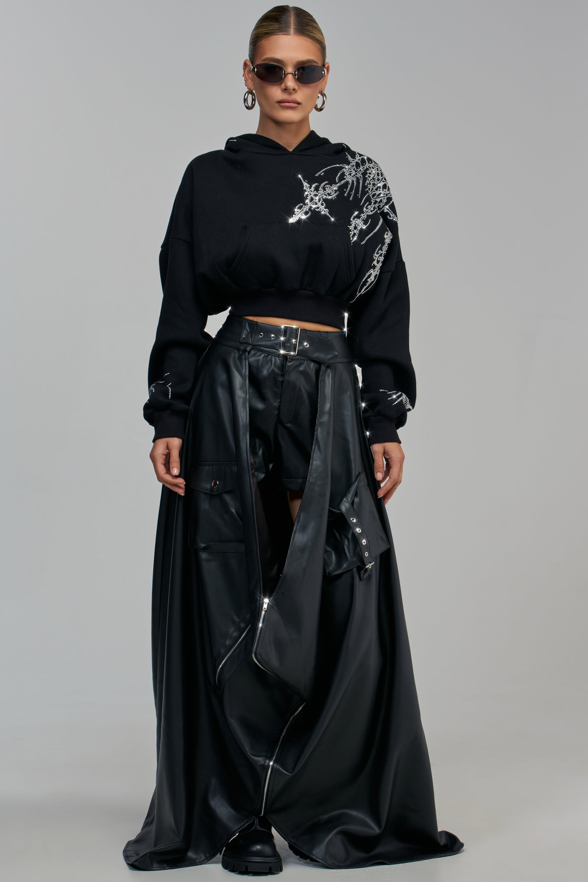 A person wearing a black cropped hoodie with silver embellishments and a black CRAZY ENOUGH MAXI SKIRT featuring cargo-style pockets and a central zipper.