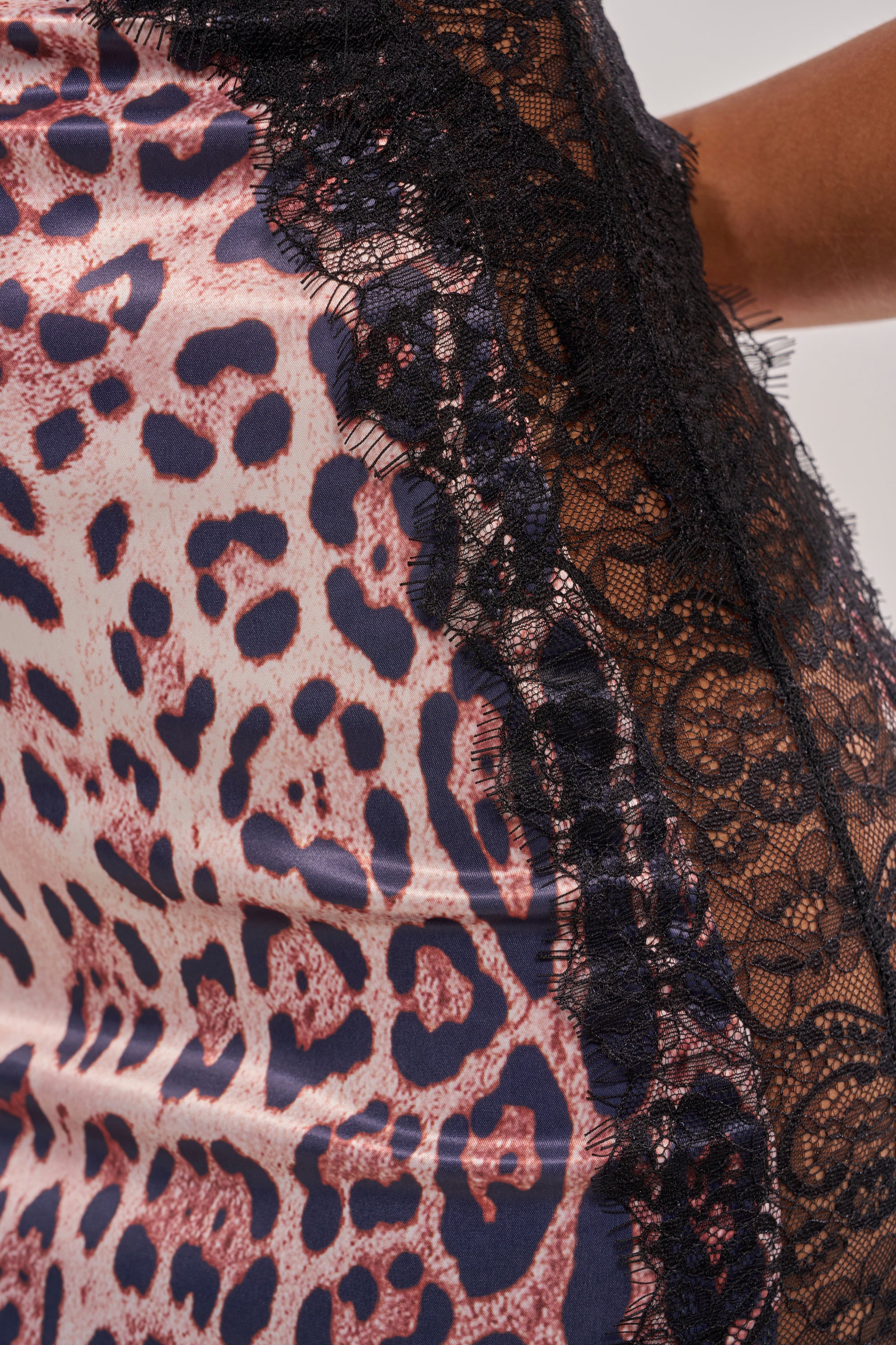Close-up of the SHOW US WHAT YOU GOT Satin Midi Dress in cheetah print, with pink and dark blue hues, featuring a decorative black lace trim along the edge. 7