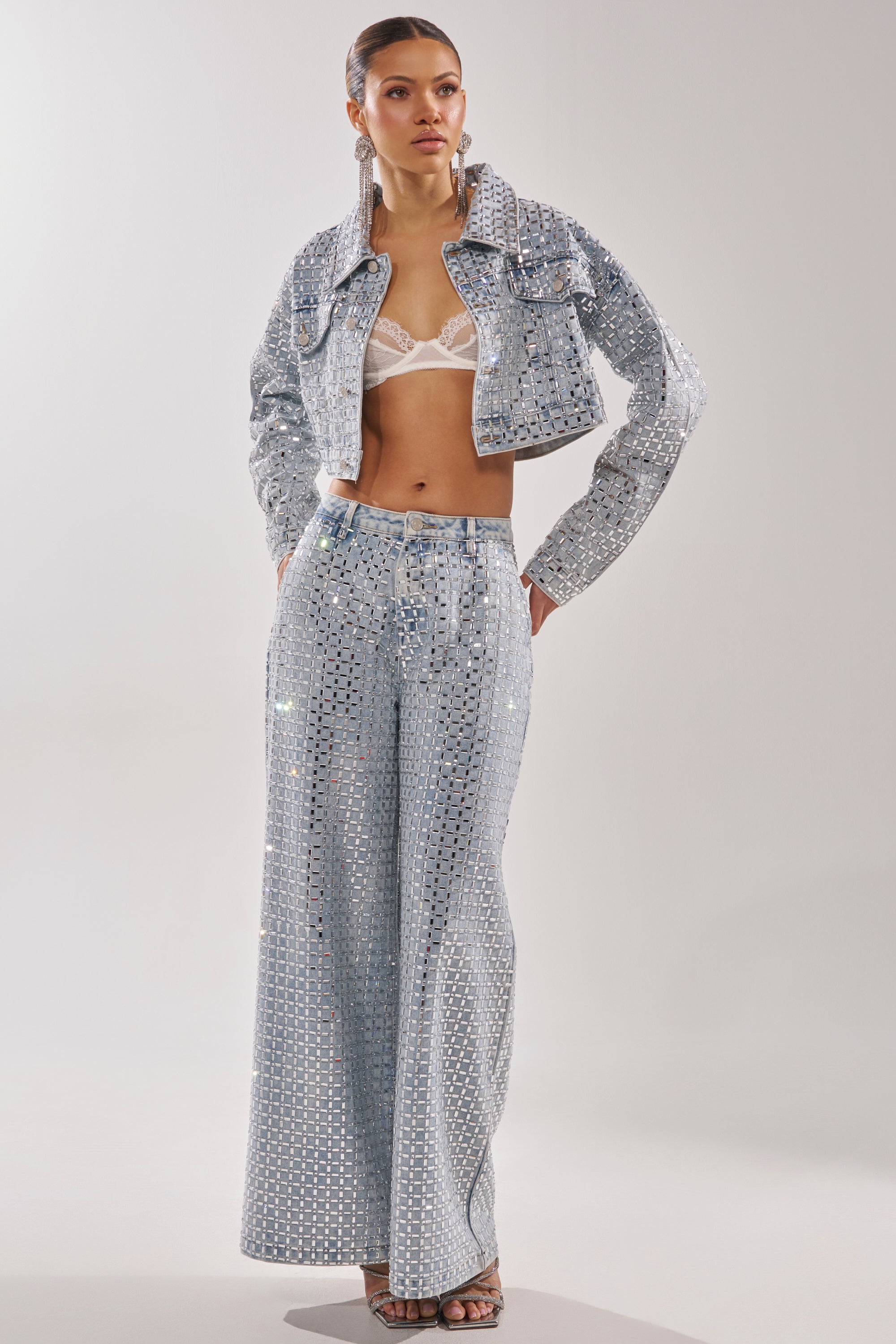 A woman wears the PICK N CHOOSE RHINESTONE DENIM JACKET over a sheer white lace bralette, paired with silver sequin wide-leg pants, hoop earrings, slicked-back hair, and strappy heels. 9