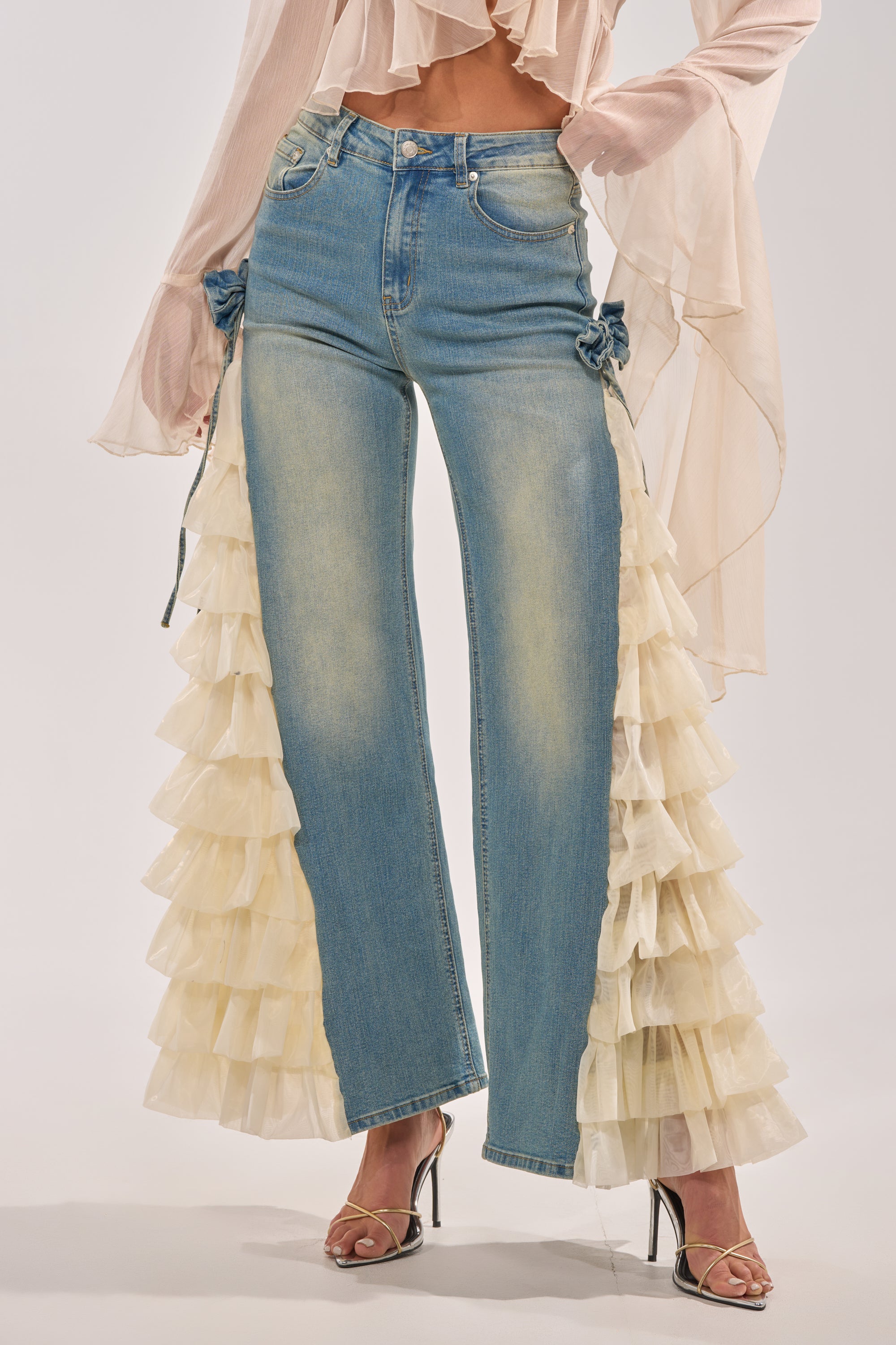 Wearing RUFFLE CITY STRAIGHT LEG DENIM with cream ruffled tulle sides, styled with a sheer flowy blouse and strappy high-heeled sandals. 2