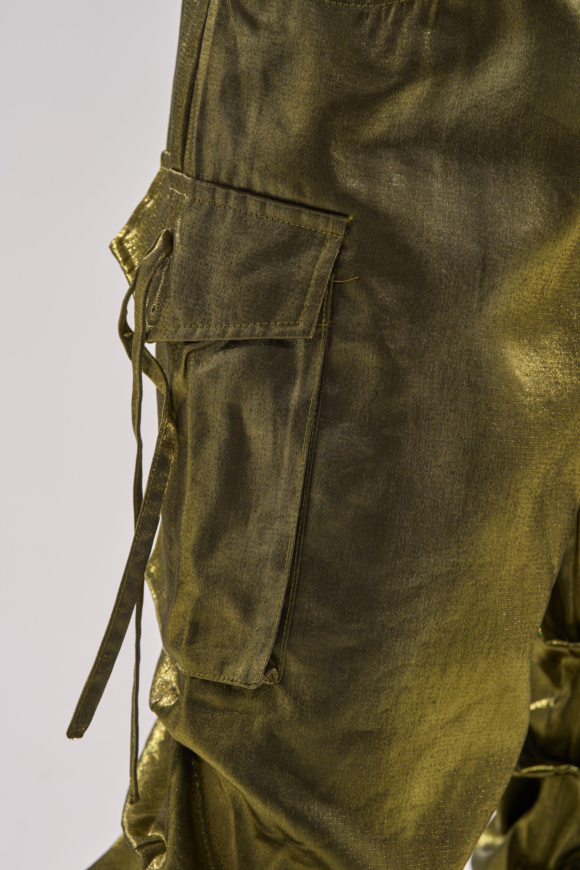 Close-up of LUCKY ONE STACKED TROUSER in shiny olive green, featuring a large flap cargo pocket and long drawstring detail, stacked against a plain light background.