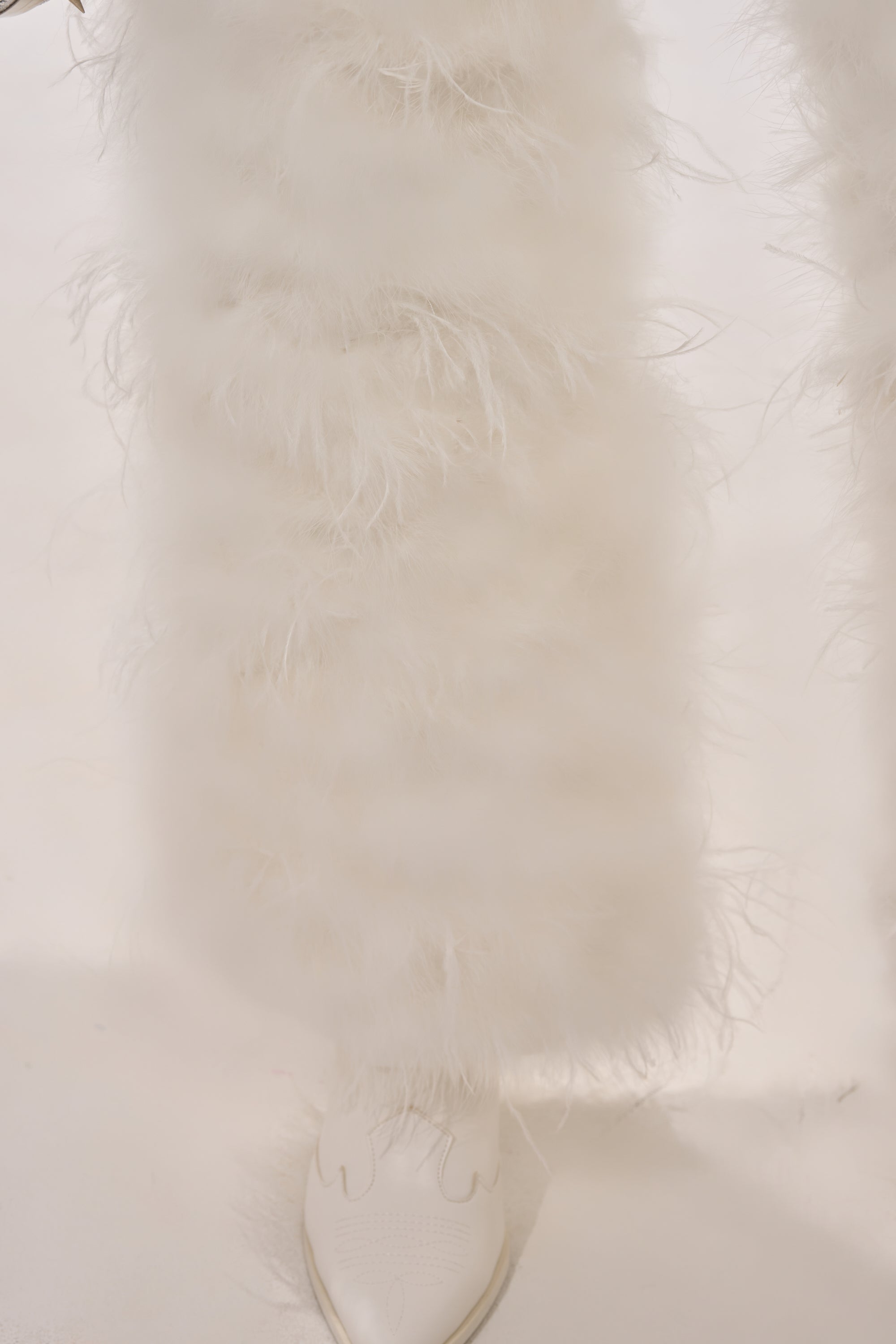 A close-up of a person's lower legs showcases the IM PERFECT FEATHER CHAPS in white with pointed-toe shoes, set against a white background—ideal for making a bold festival fashion statement. 11