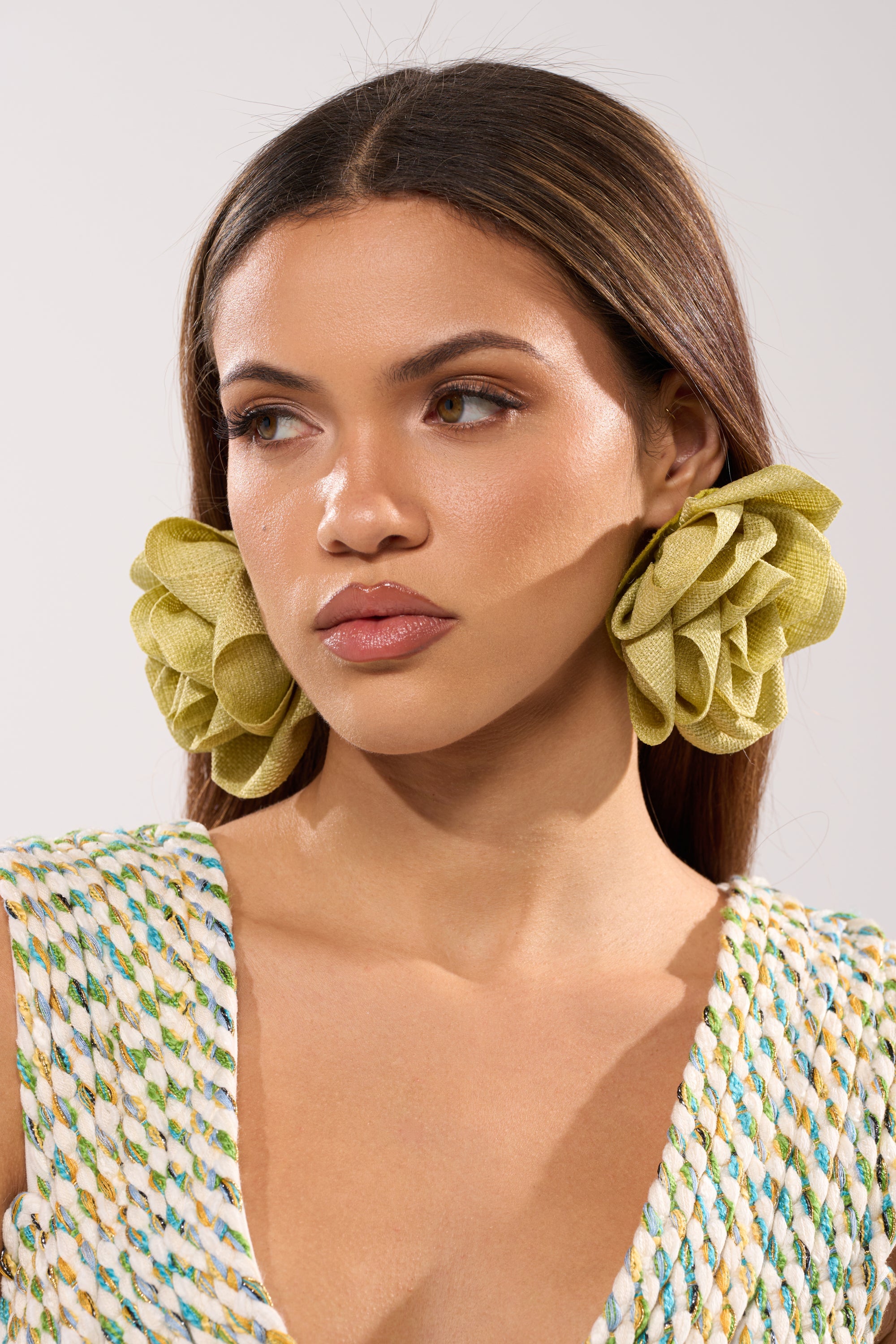 A woman with straight brown hair wears the large, woven AT BRUNCH EARRING and a sleeveless, multicolored woven top, gazing slightly to the side against a plain light background. 2