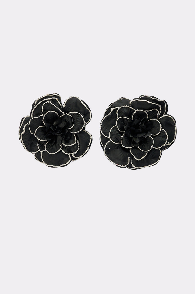 Two DRAMA EARRING pieces in black fabric, featuring layered petals and white-edged details, displayed on a plain light gray background.