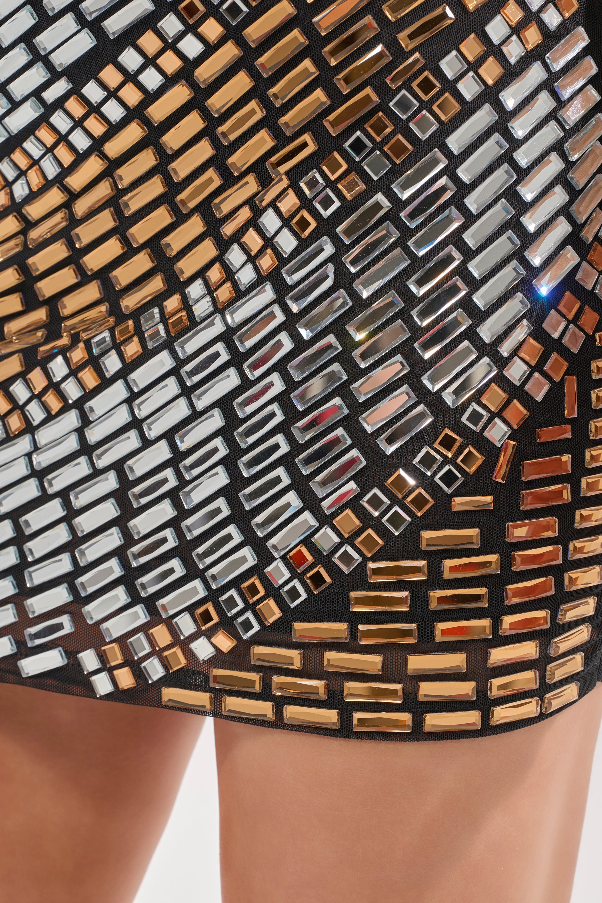 Close-up of the CAN'T BEAT MY OUTFIT EMBELLISHED MINI DRESS, featuring metallic gold and silver rectangular sequins in geometric patterns, with a glimpse of a person's legs visible below the dress hem. 7
