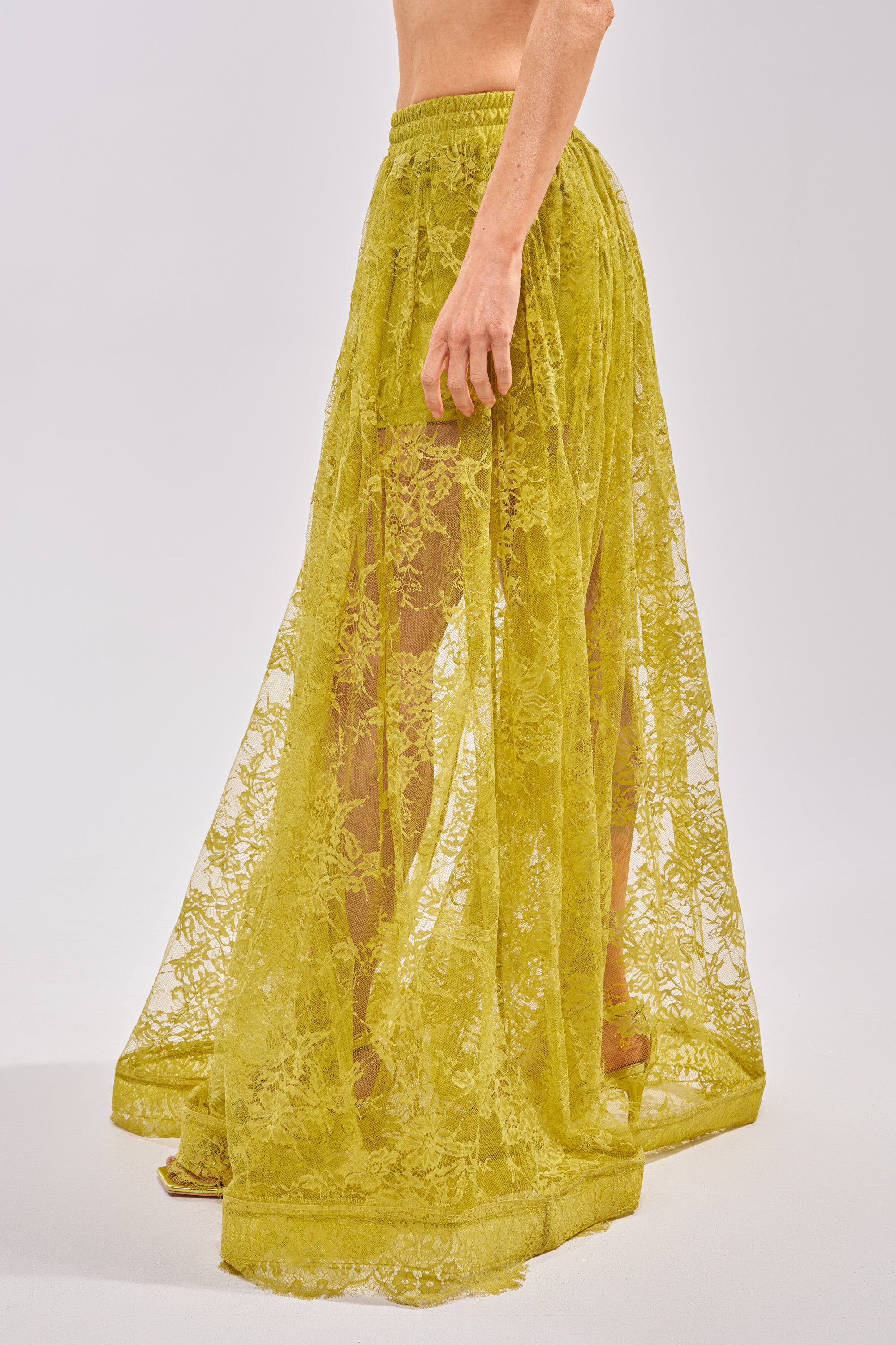 Model wears the HANNAH LACE MAXI SKIRT, a sheer chartreuse yellow floral lace design with an elastic waistband, shown from the waist down against a light background—perfect for springtime looks. 4