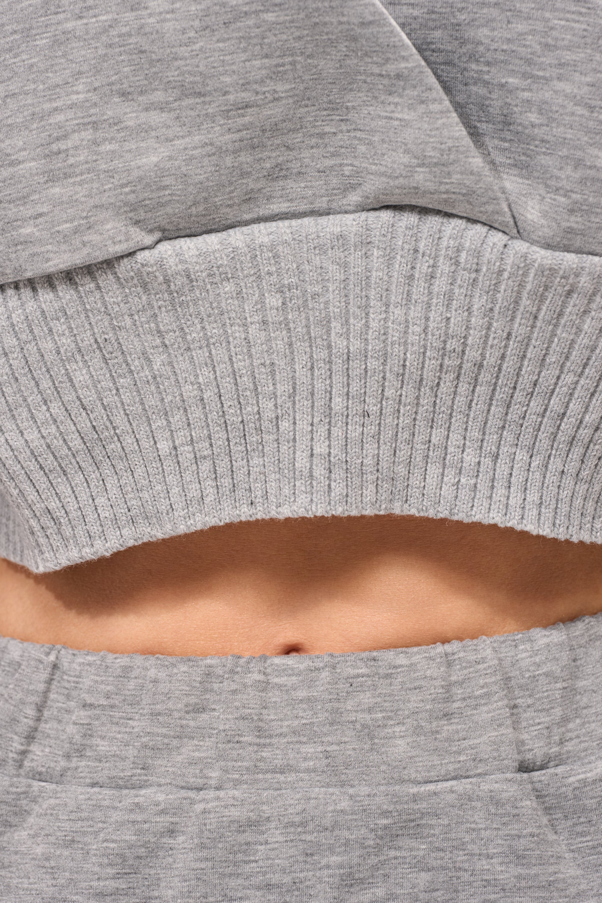 Close-up of a person's bare midriff, showing part of their abdomen and navel, framed by gray sweatpants and the ribbed hem of the NO WORK ALL PLAY SCUBA SWEATSHIRT. 7