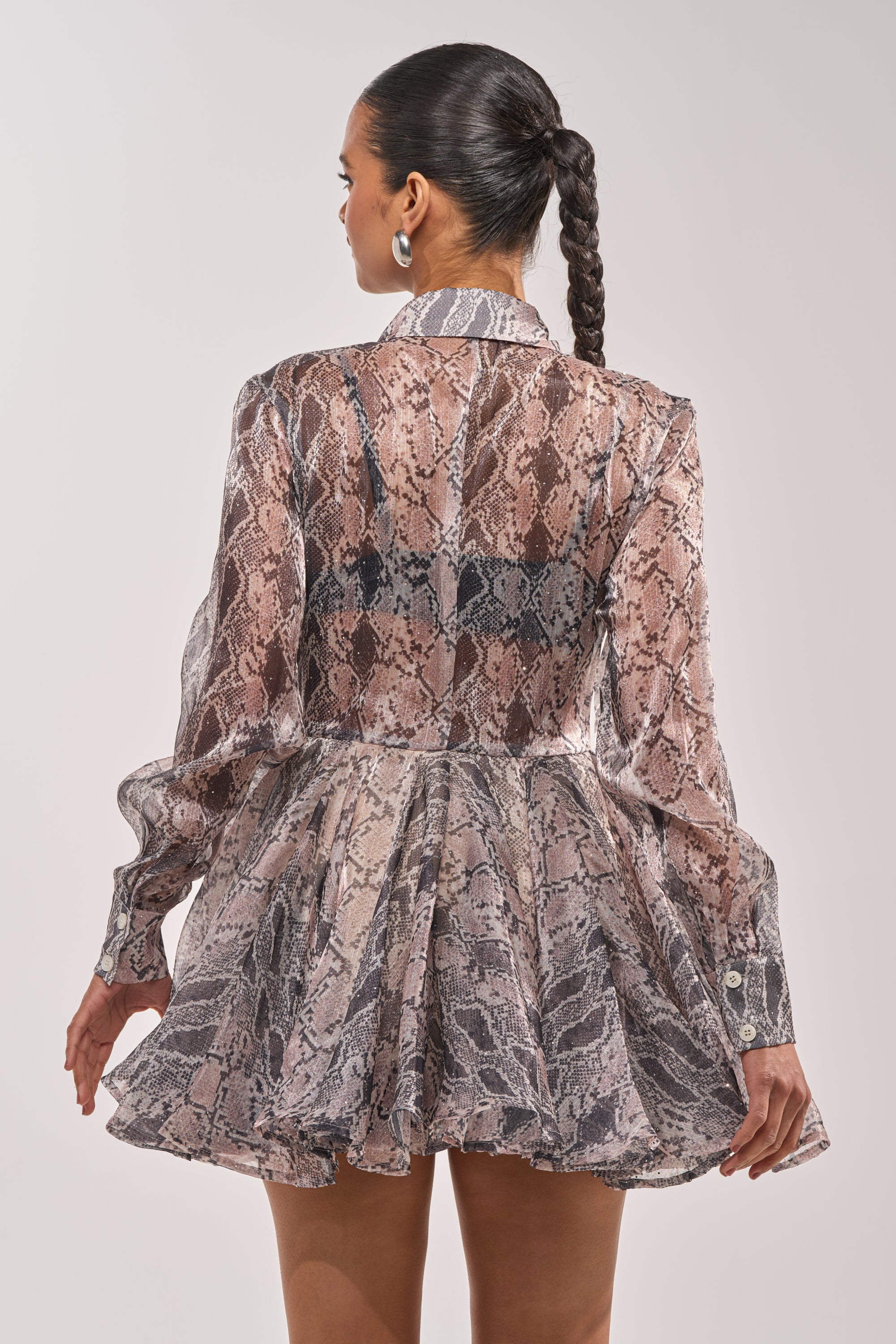 A woman with a braided ponytail is seen from the back wearing the WILD RHYTHM SNAKE PRINT MINI DRESS—a long-sleeve, collared, fit-and-flare style in snakeskin print—against a plain light background. 5