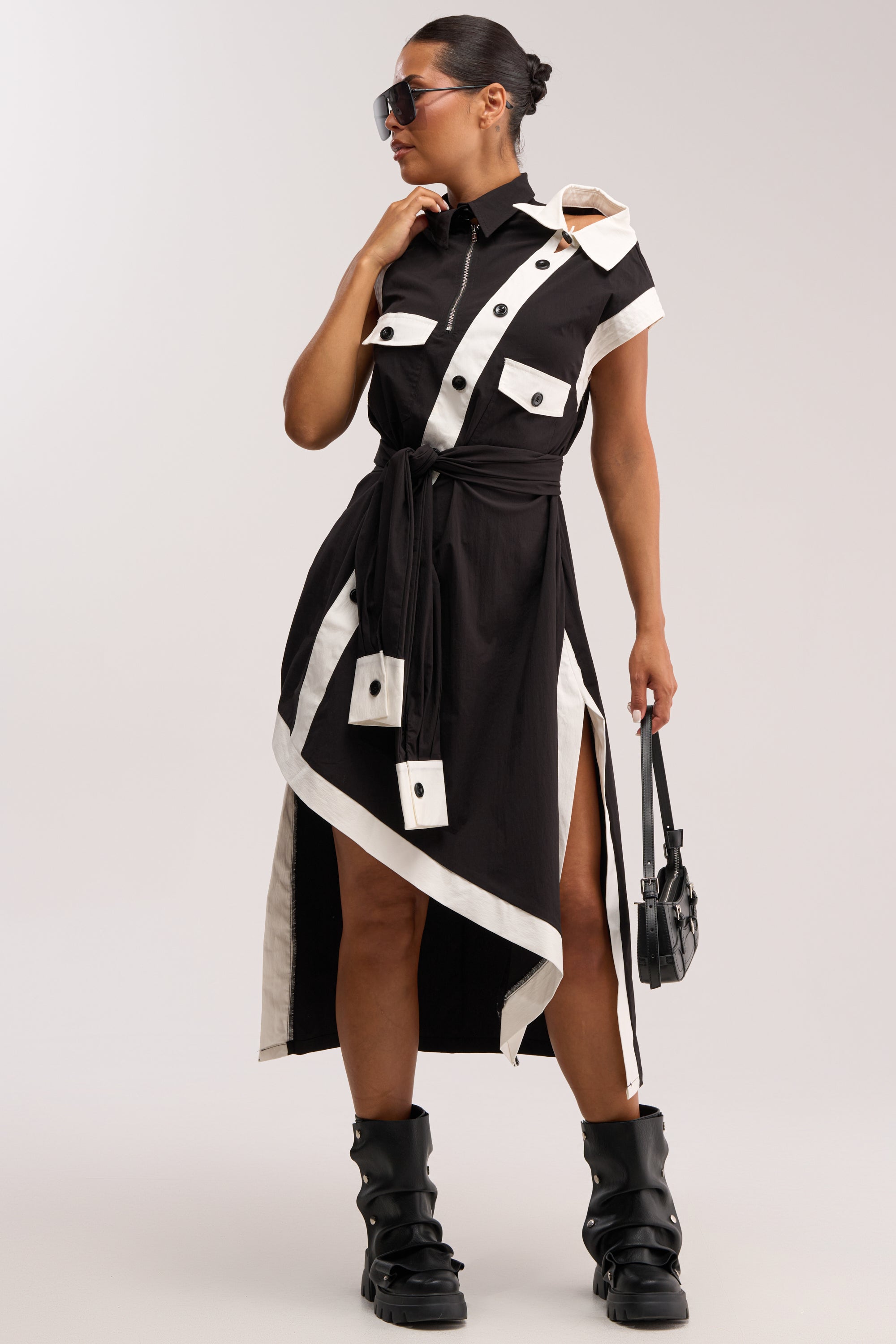 Wearing the NO FILTER NEEDED BUTTON UP MAXI DRESS, black boots, sunglasses, and a small black handbag, this person exudes confidence and effortless chic against a plain background—a modern take on fashion-forward workwear.