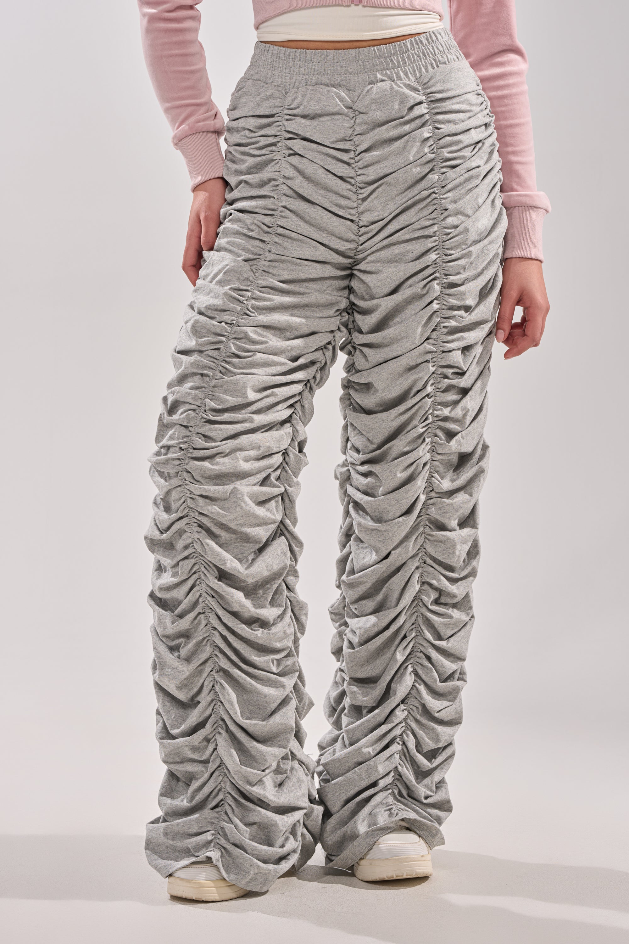 Wearing the IM THAT TYPE RUCHED JOGGER in high-waisted heather grey with wide legs and white sneakers, paired with a light pink long-sleeve crop top for a fresh, stylish look. 0