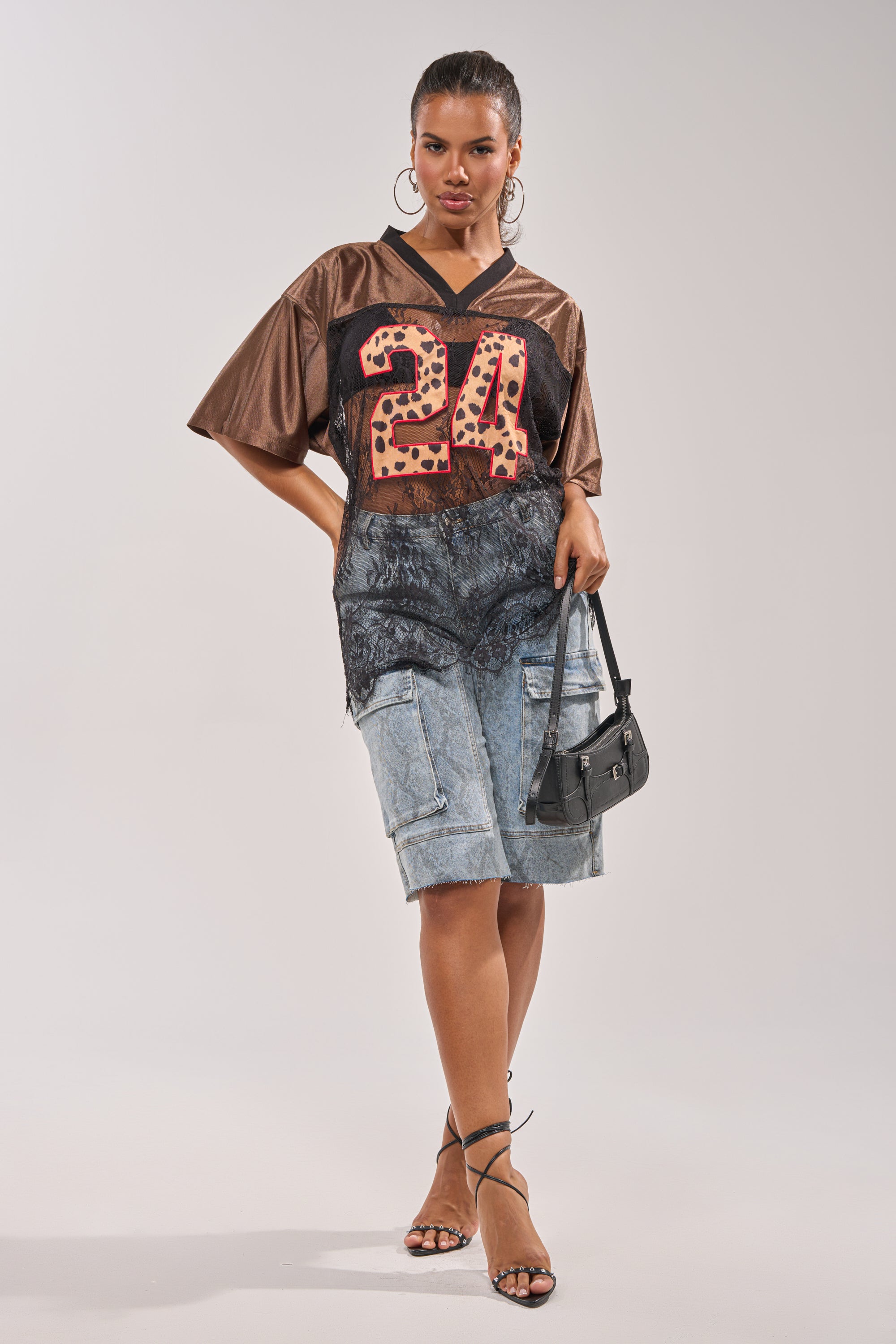 A woman poses in the LUCKY 24 JERSEY, styled with a lace-trimmed denim skirt featuring cargo pockets, strappy heels, hoop earrings, and a small black handbag. 8